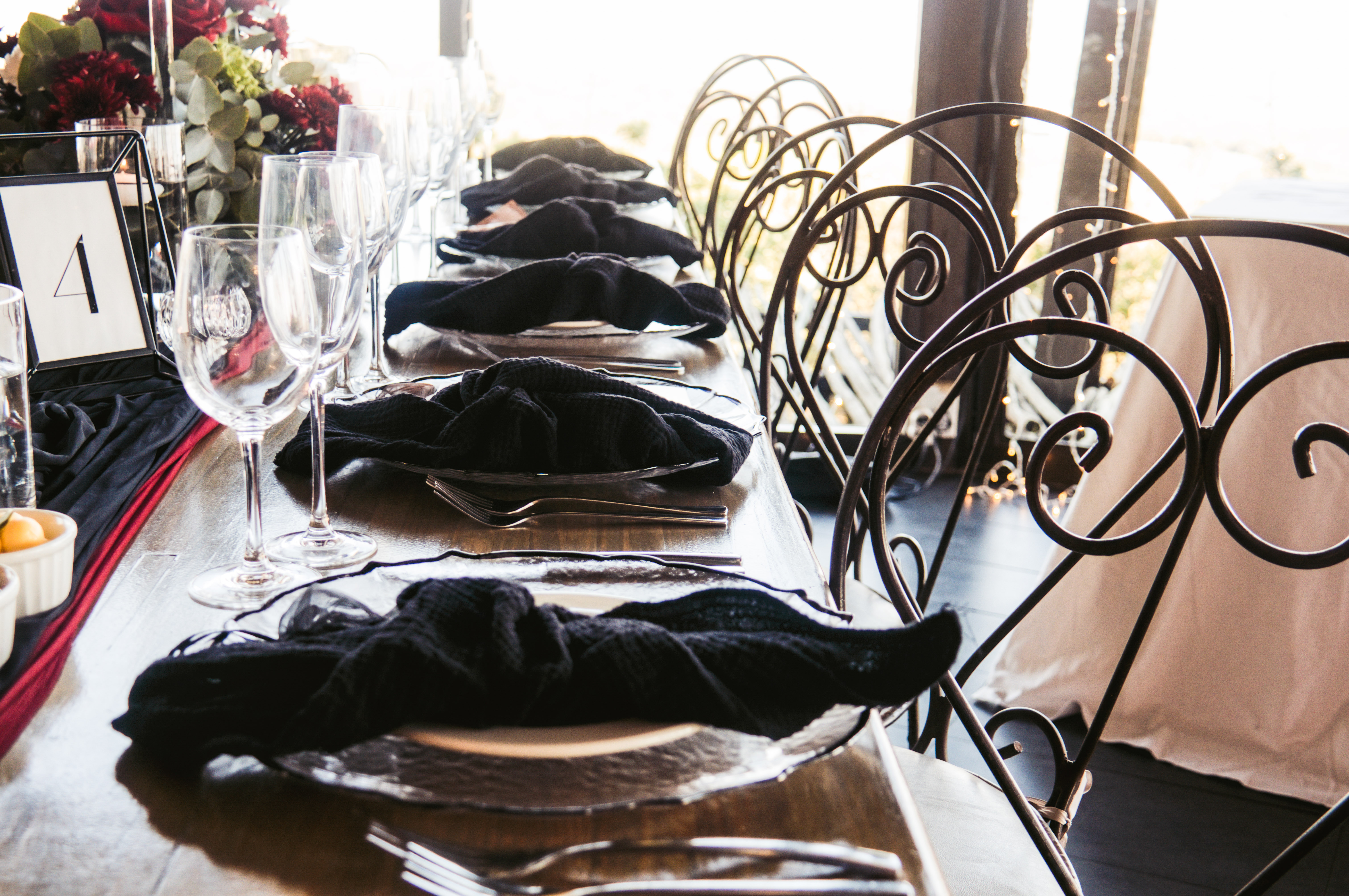 Black napkin place settings beside ornate iron chairs