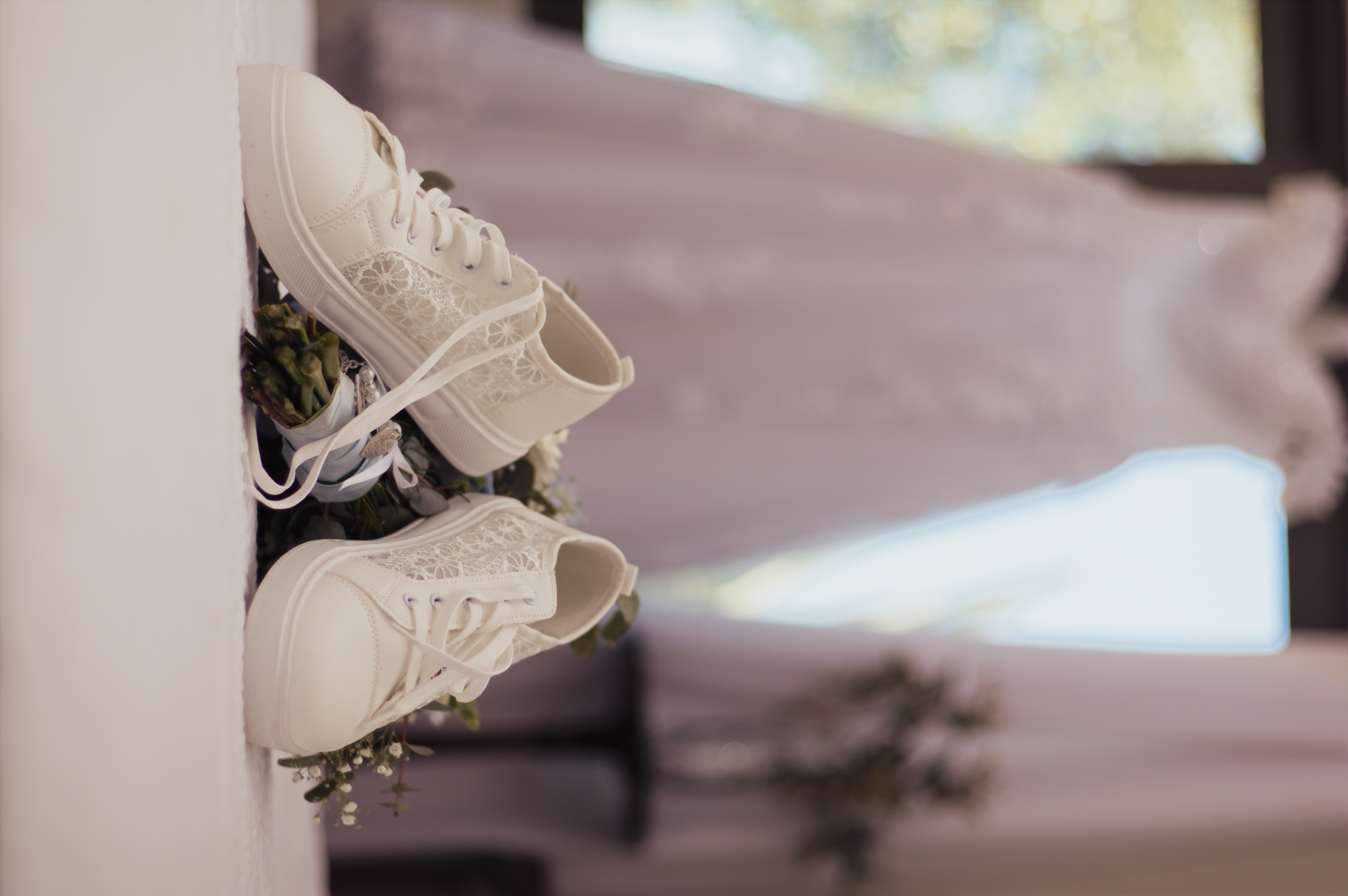 Lace bridal sneakers and bouquet in front of the wedding gown