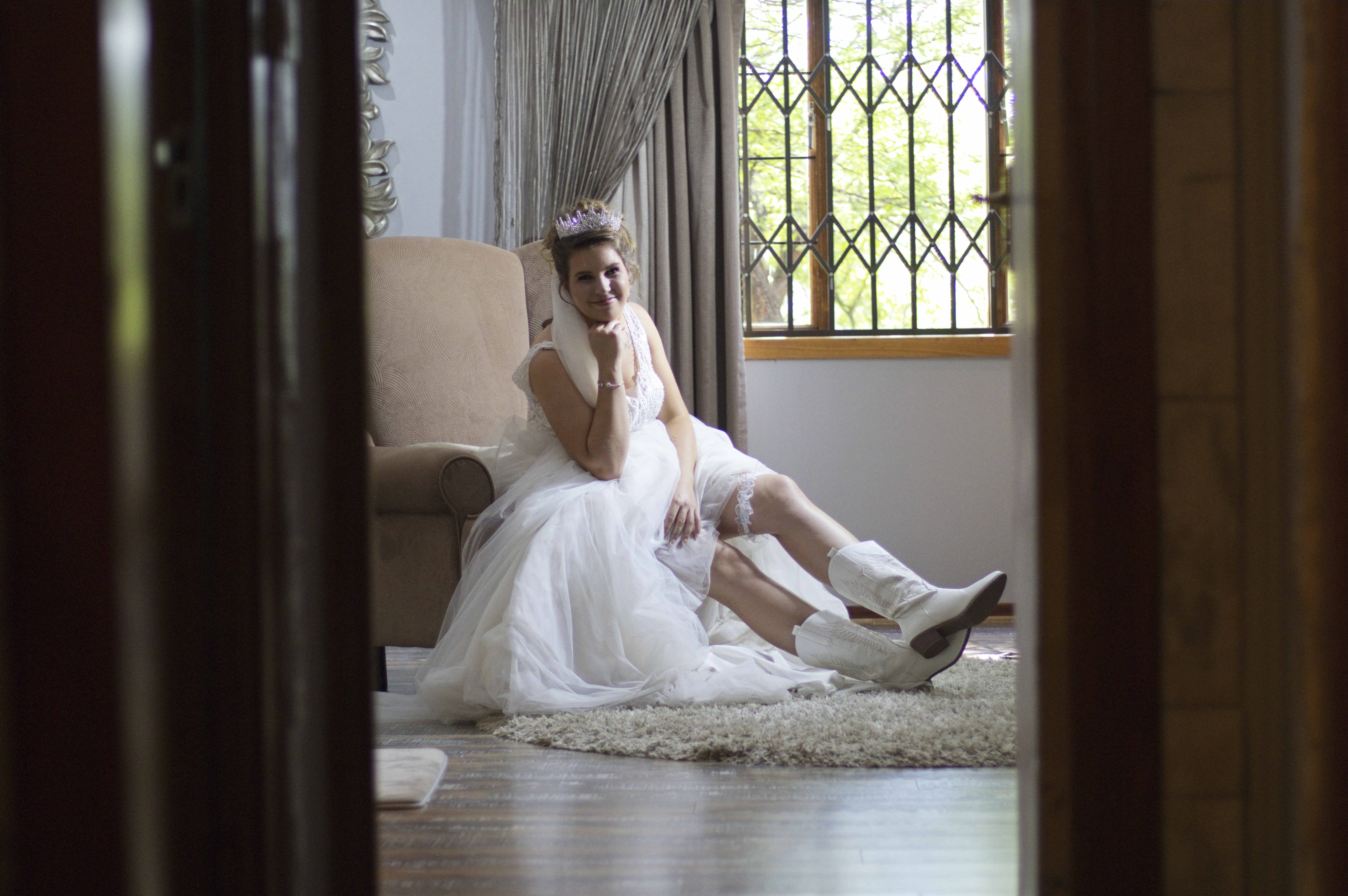 Bride in white cowboy boots seen through a doorway