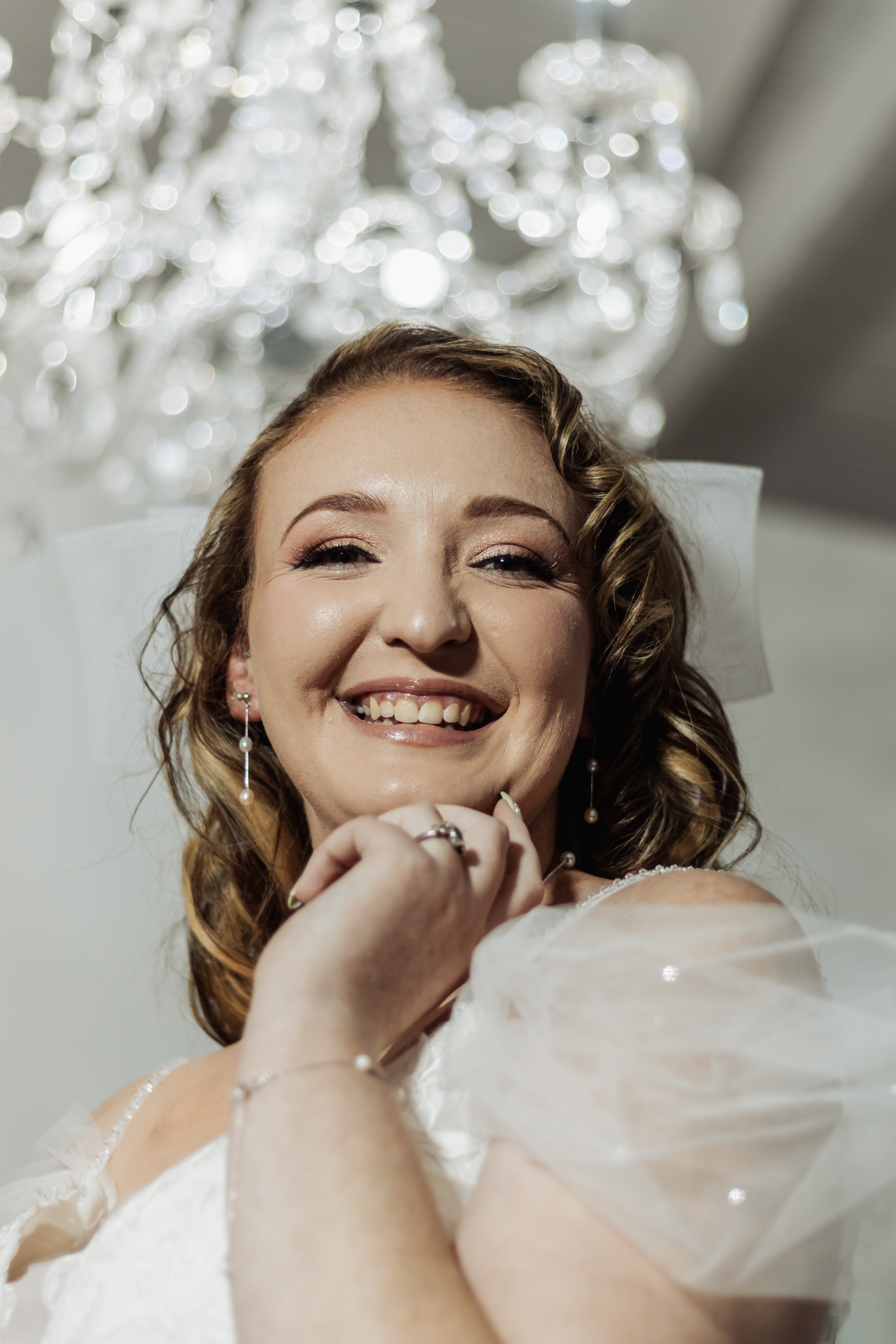 Smiling bride beneath a sparkling crystal chandelier