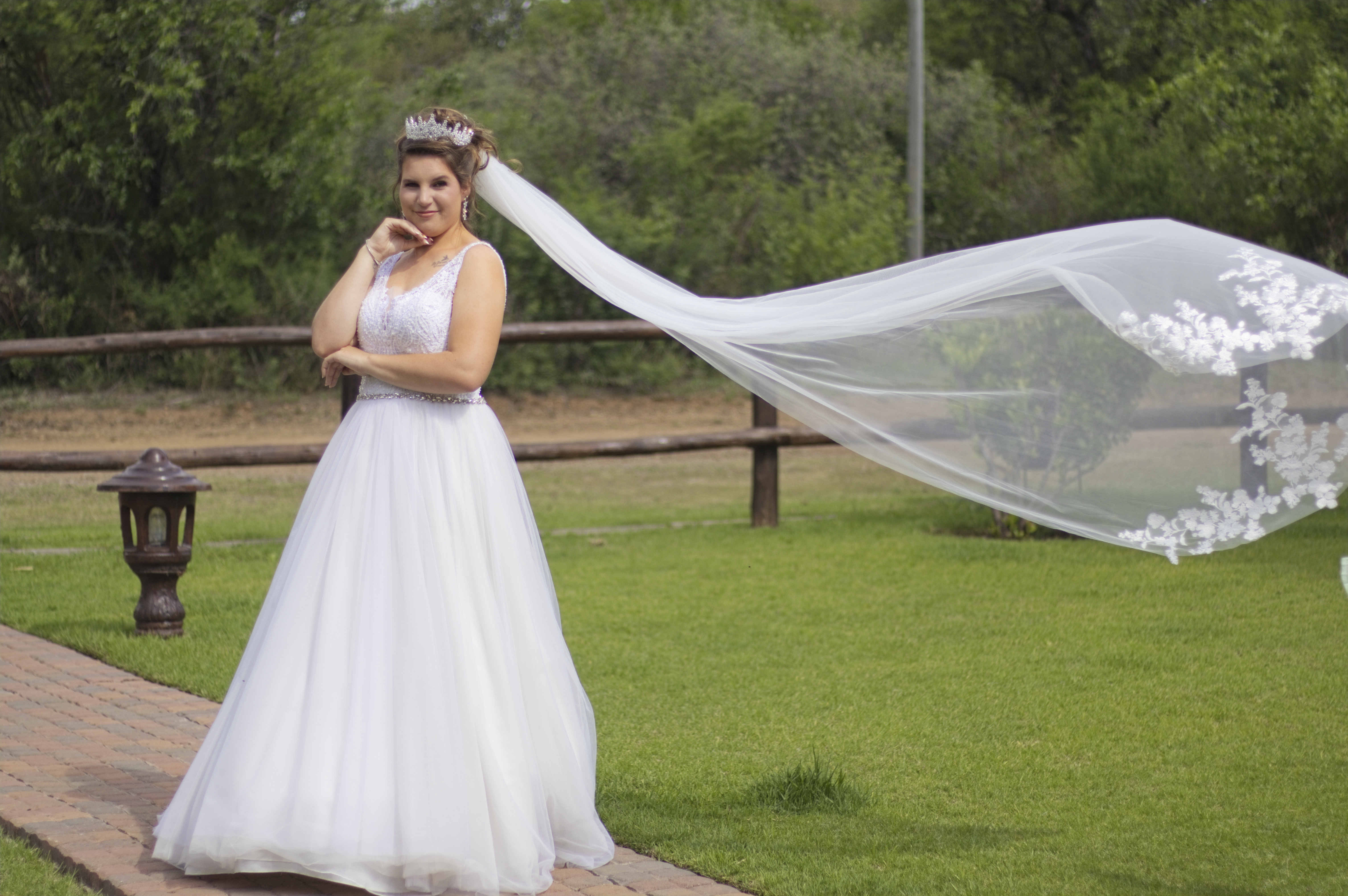 Bride in the garden with her long veil flowing in the wind