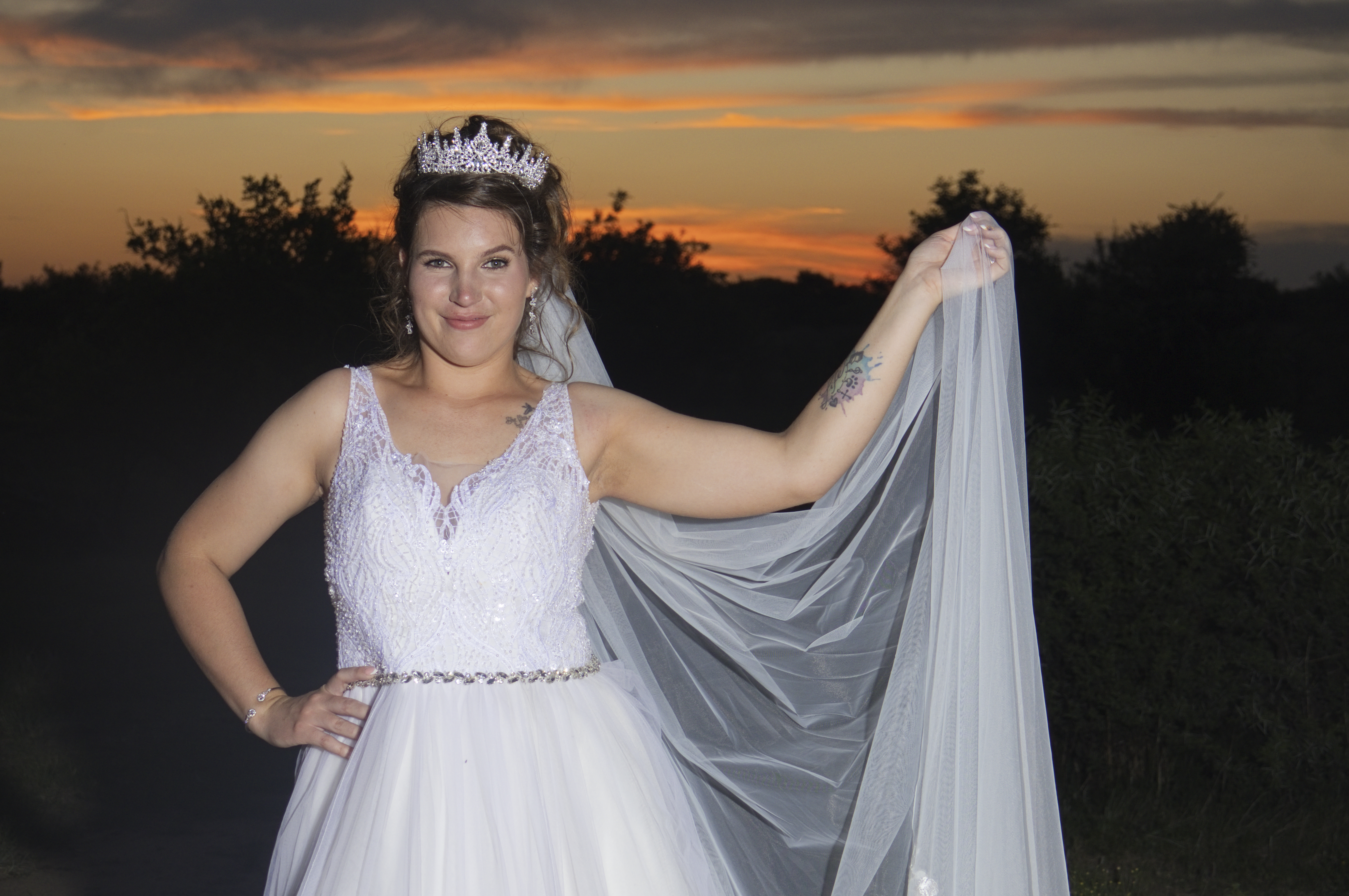 Bride holding out her veil against an orange sunset