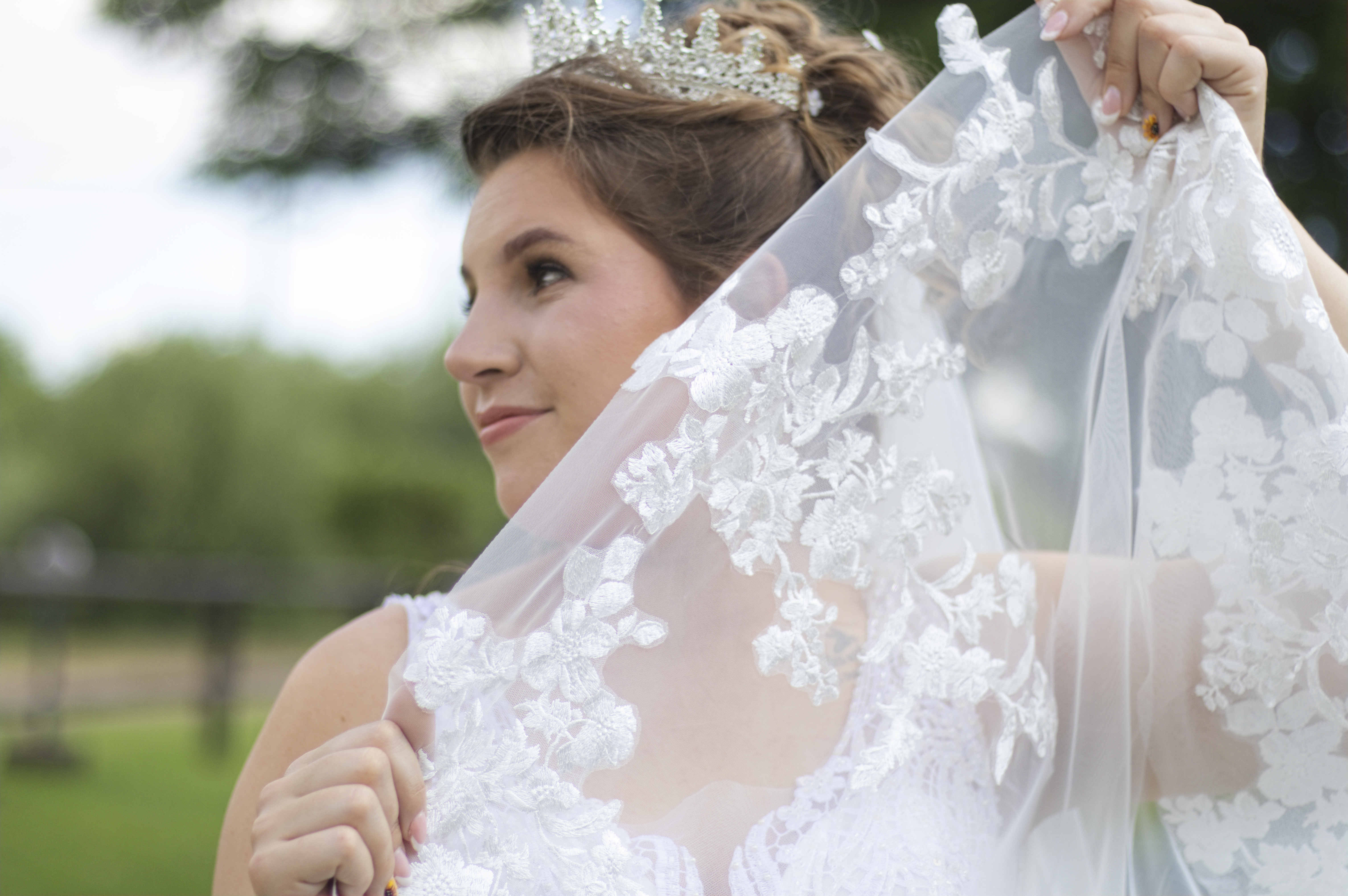 Bride in profile holding up her lace veil