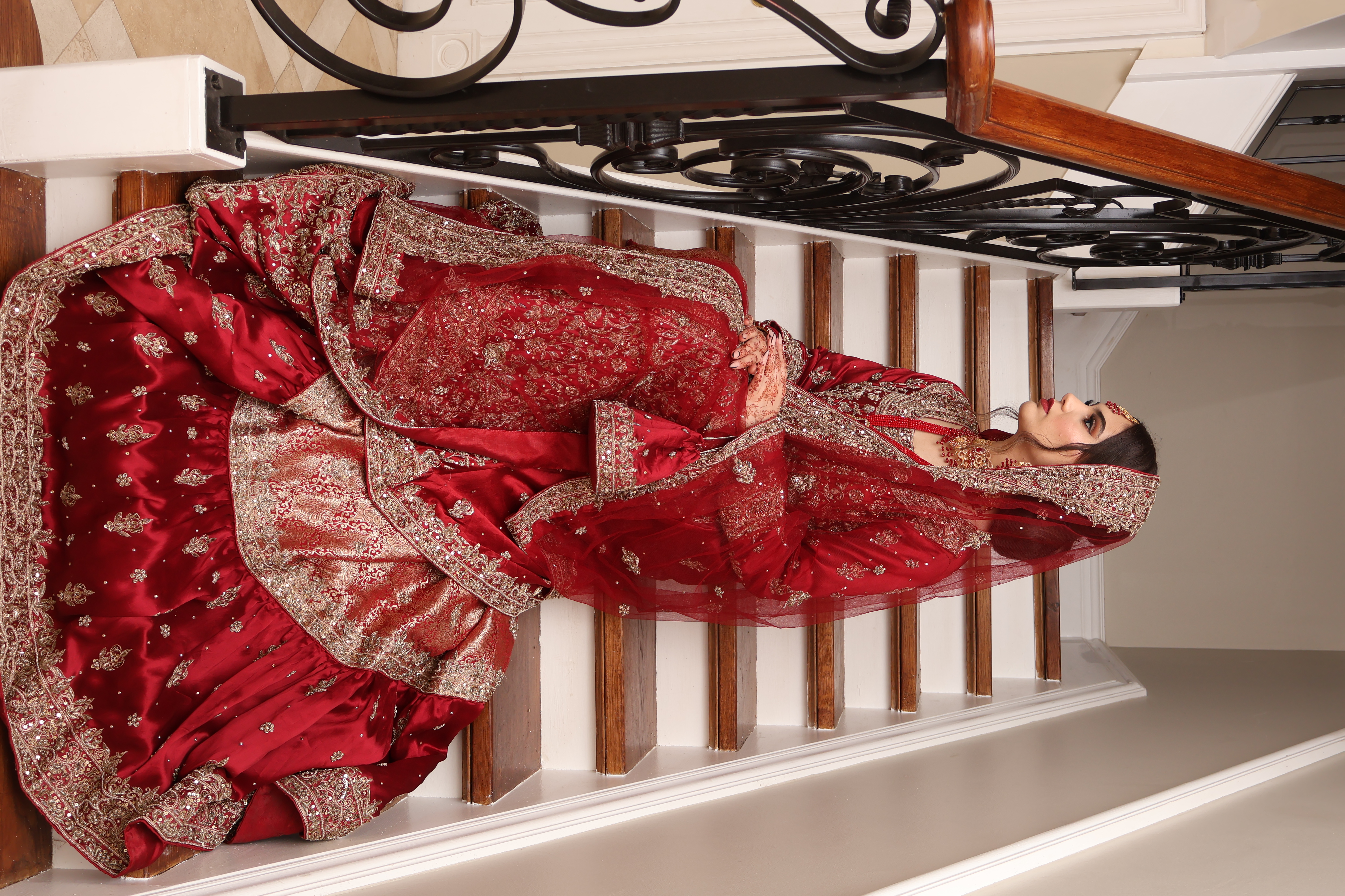 Bride seated on a staircase in a flowing red bridal lehenga