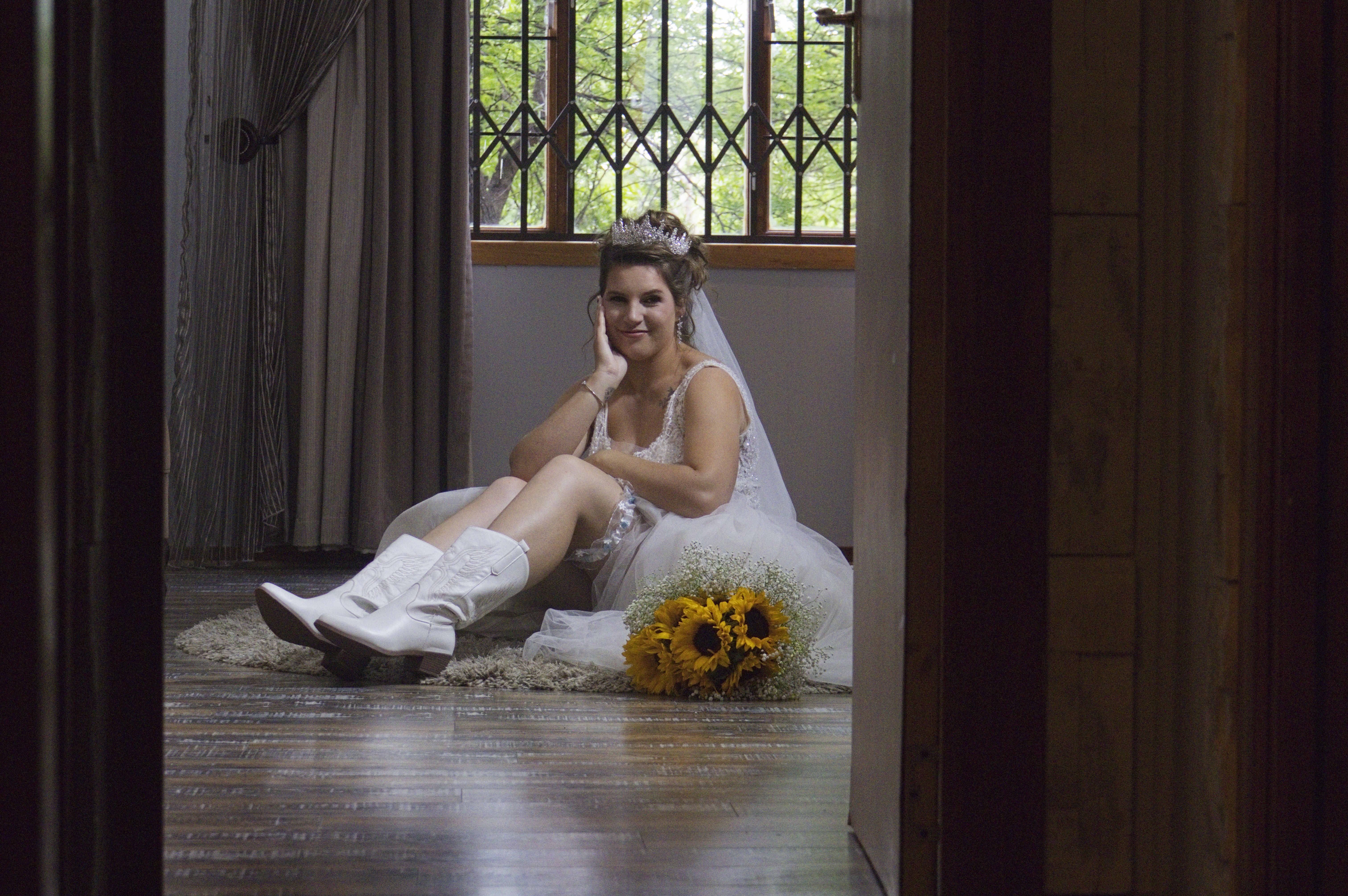 Bride seated on the floor with white boots and sunflowers