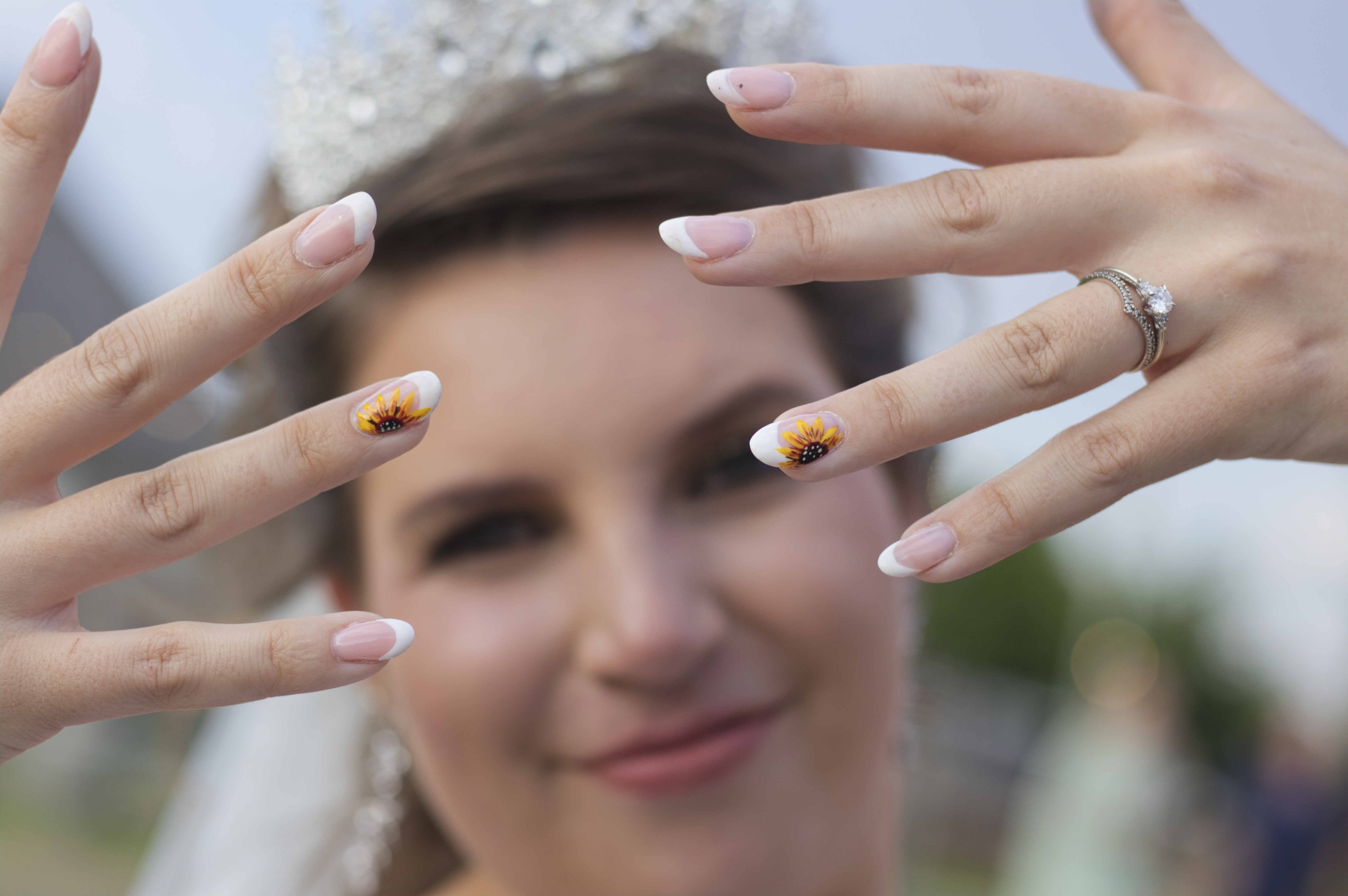 Bride showing her sunflower nail art and engagement ring