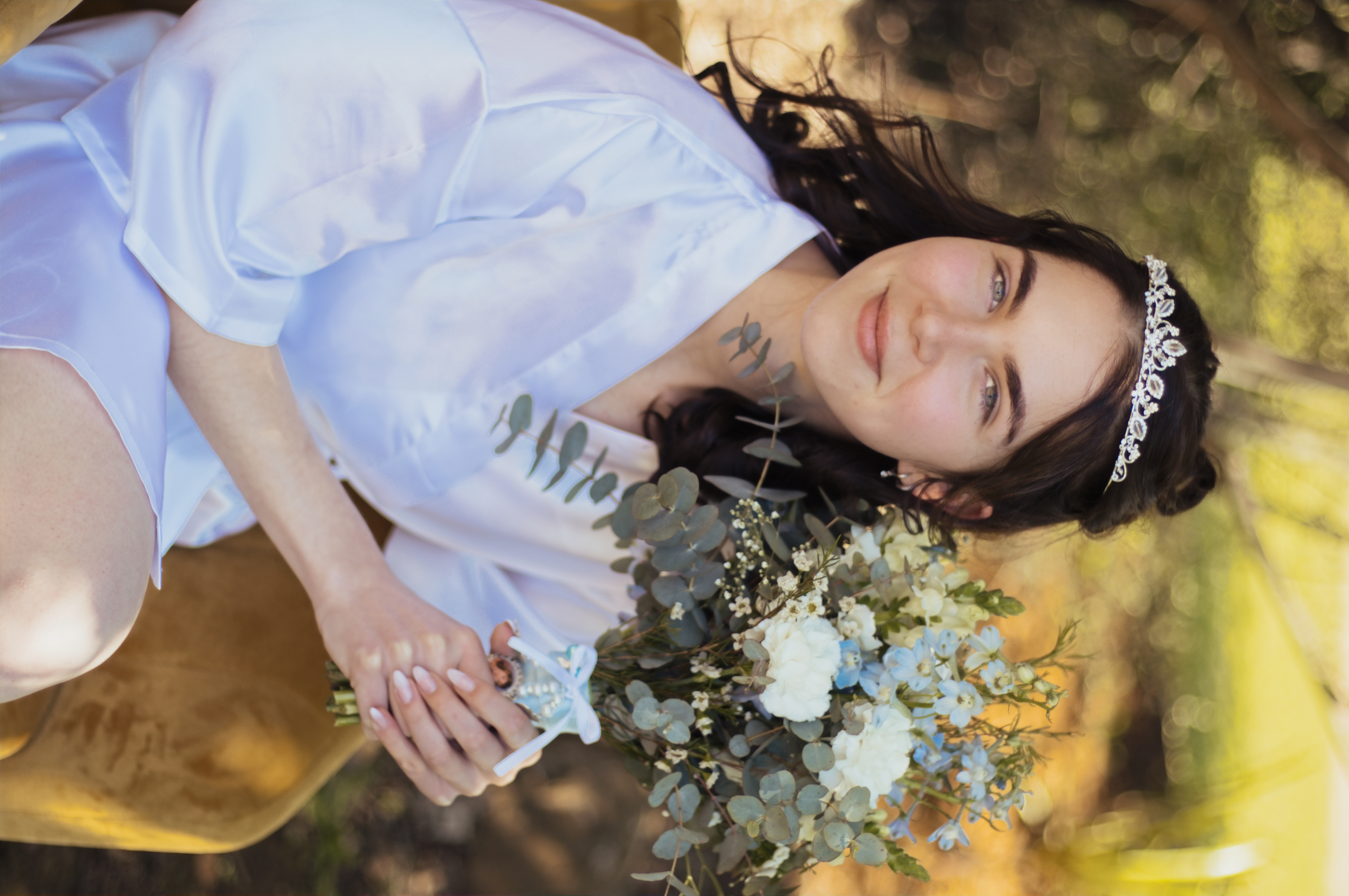 Bride in a tiara and robe holding a blue and white bouquet