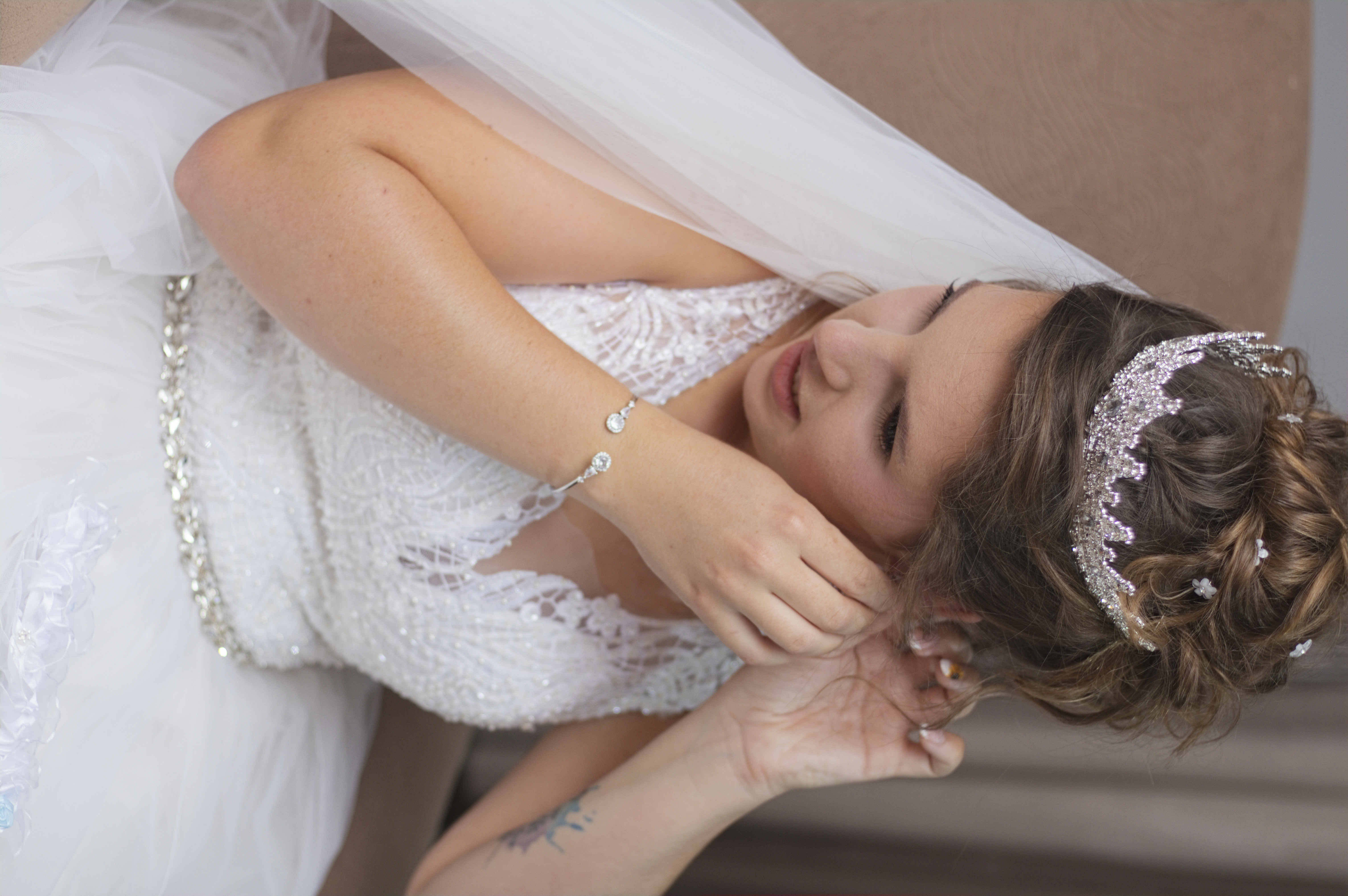 Bride in a crystal tiara putting on her earrings