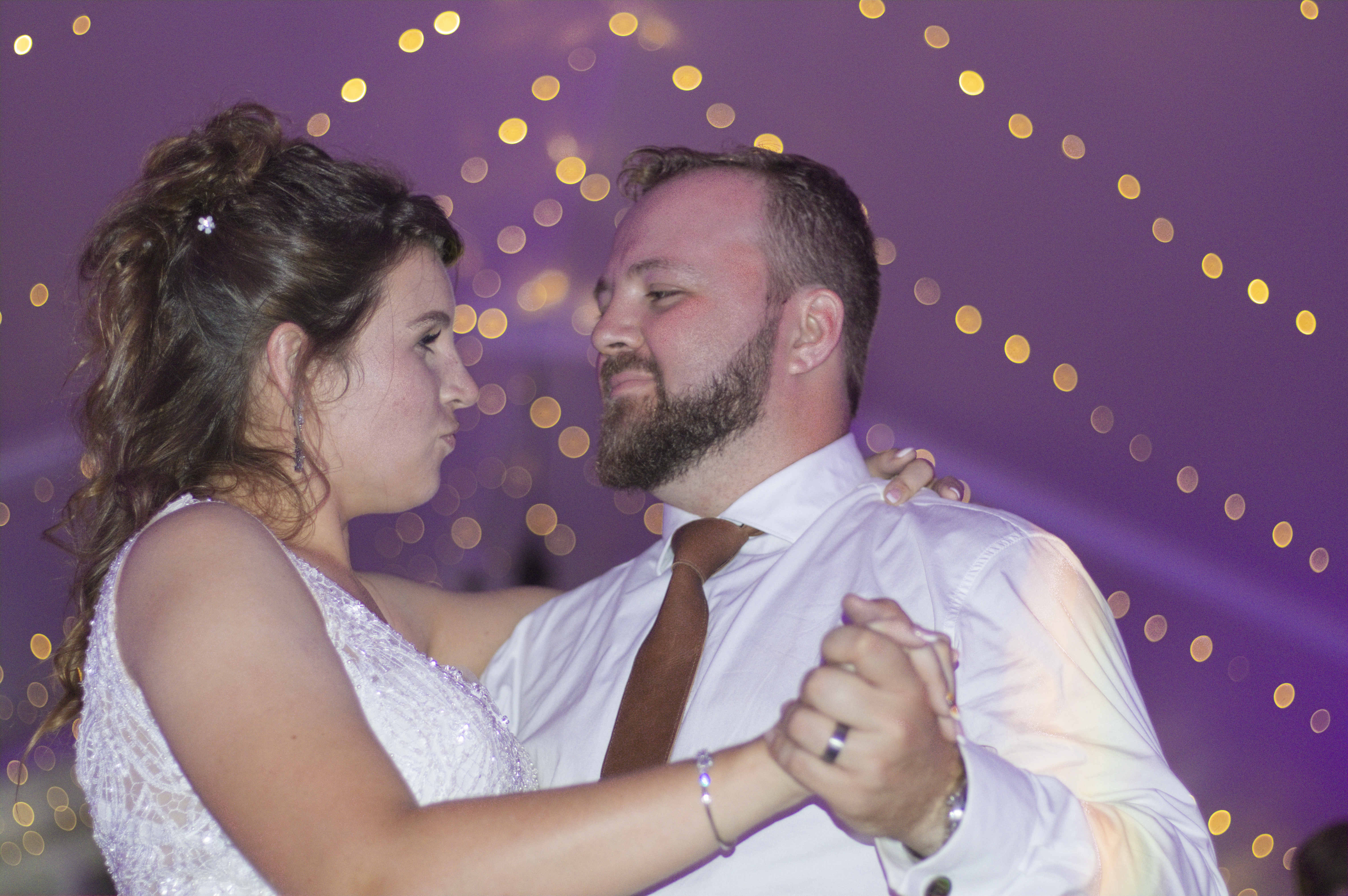 Playful couple dancing under purple fairy lights