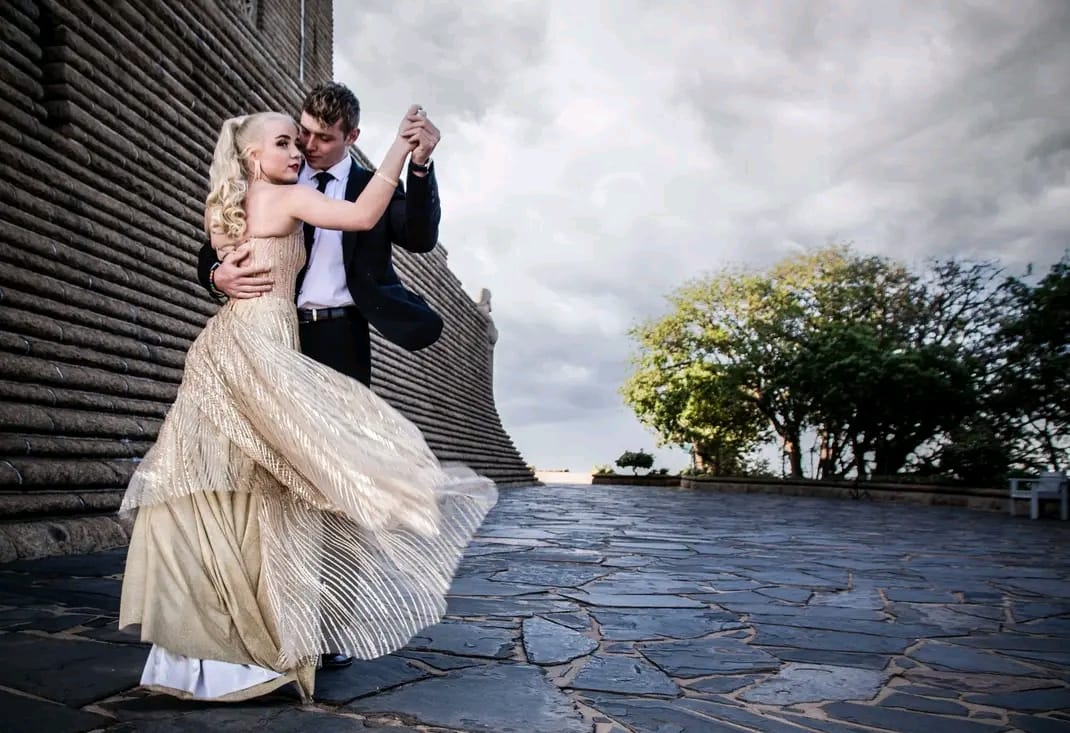 Couple dancing beside a stone monument, her gold gown swirling