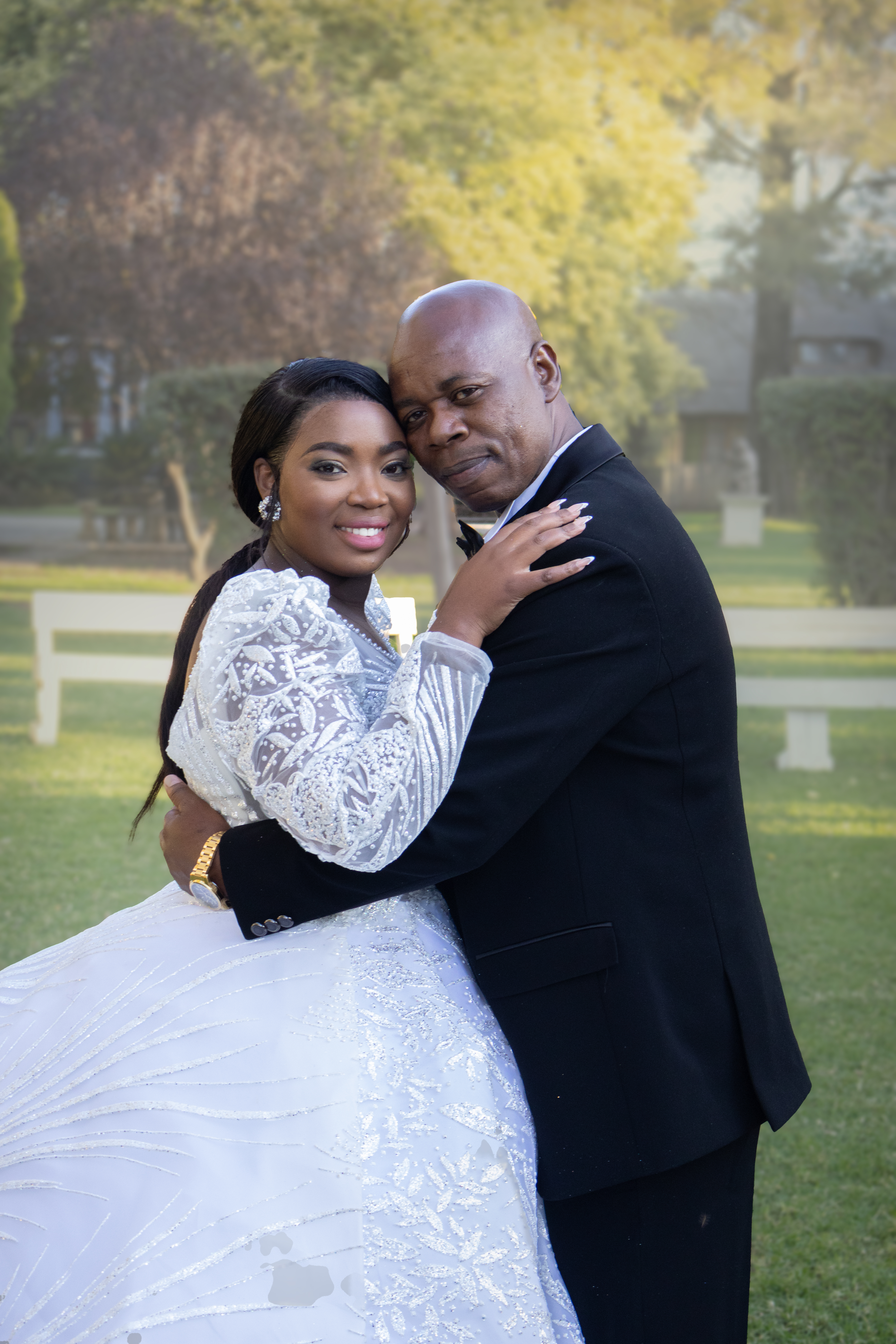 Bride and groom embracing cheek to cheek in a golden garden