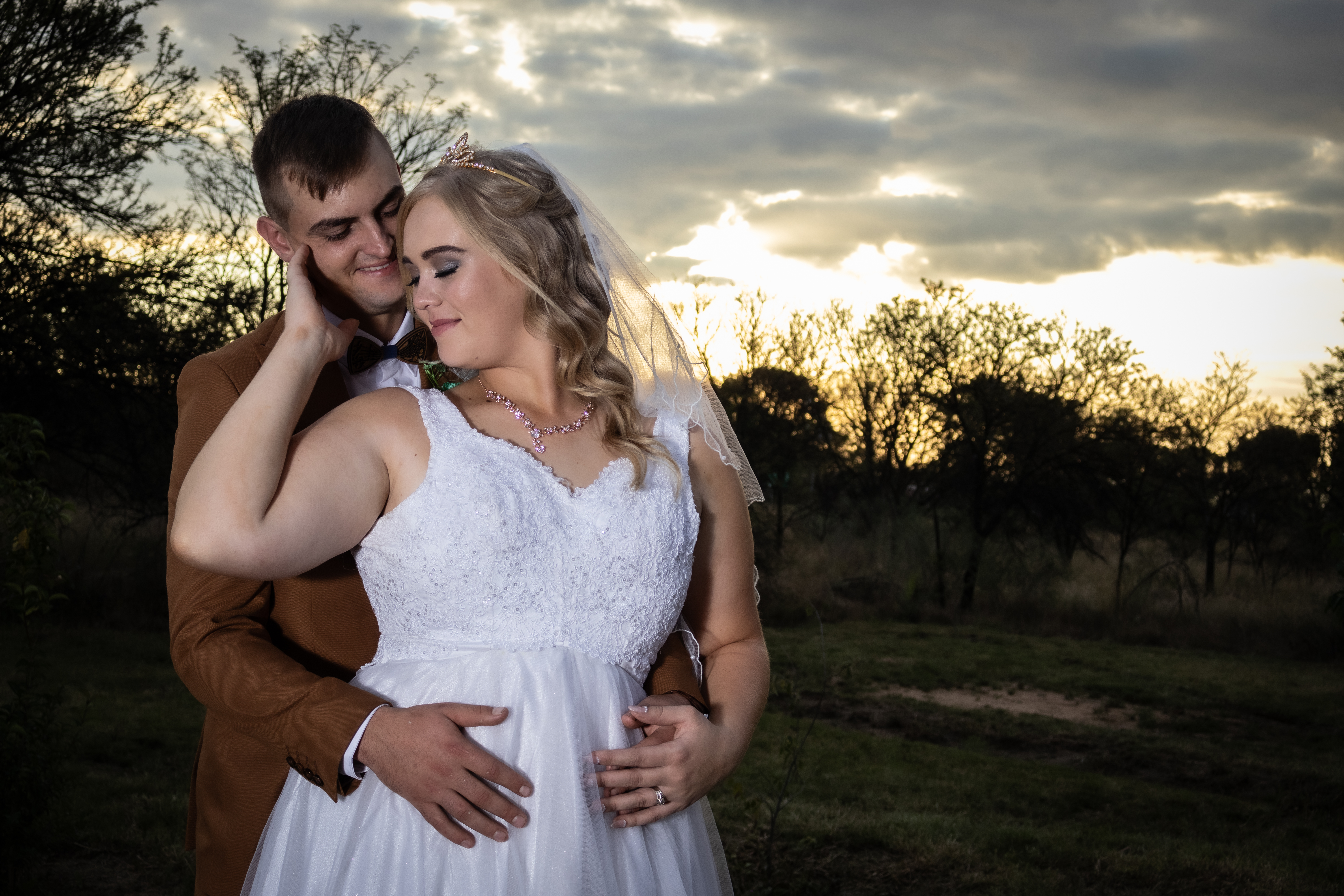 Couple embracing against a dramatic sunset sky