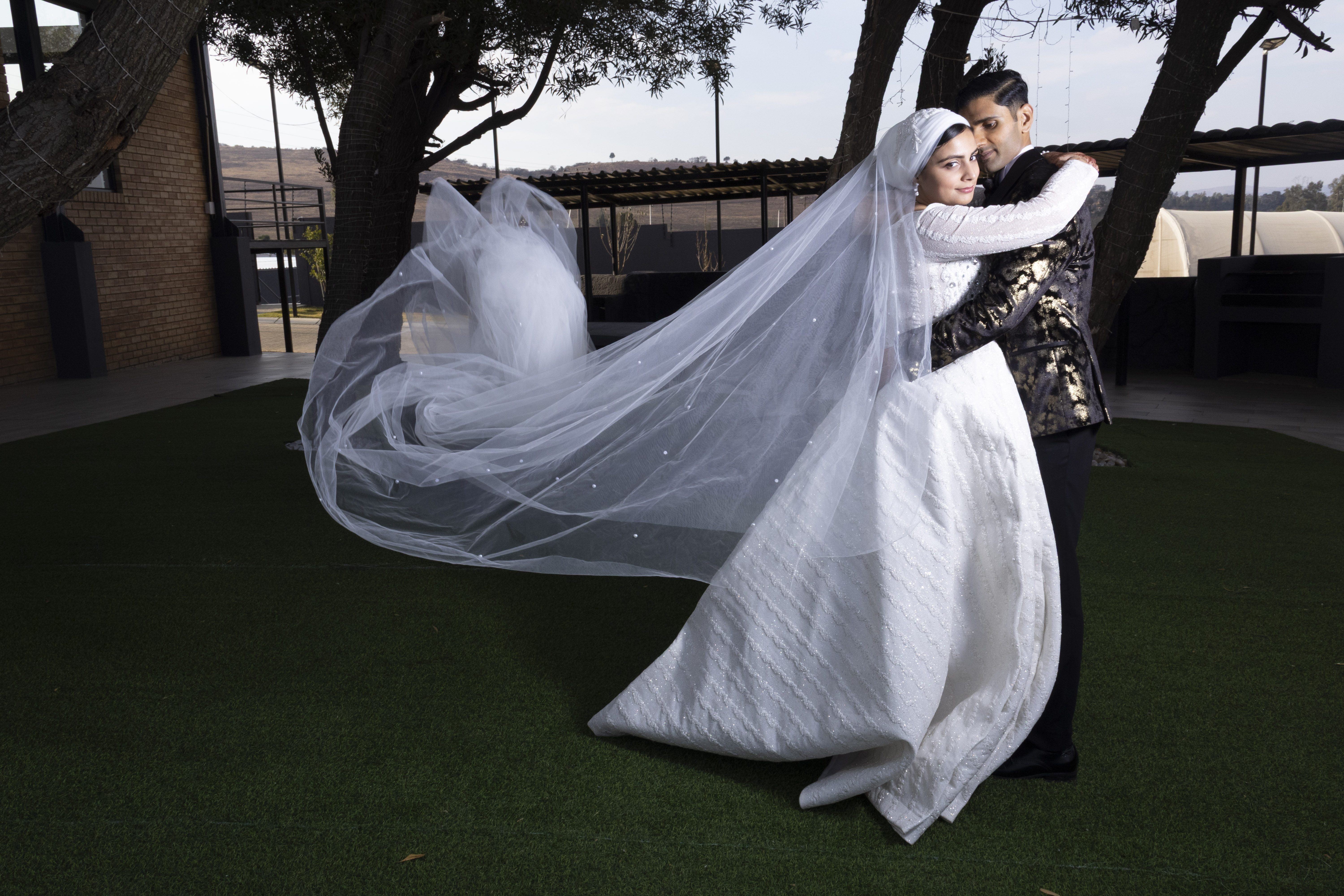 Couple embracing as the bride's long veil flows in the wind