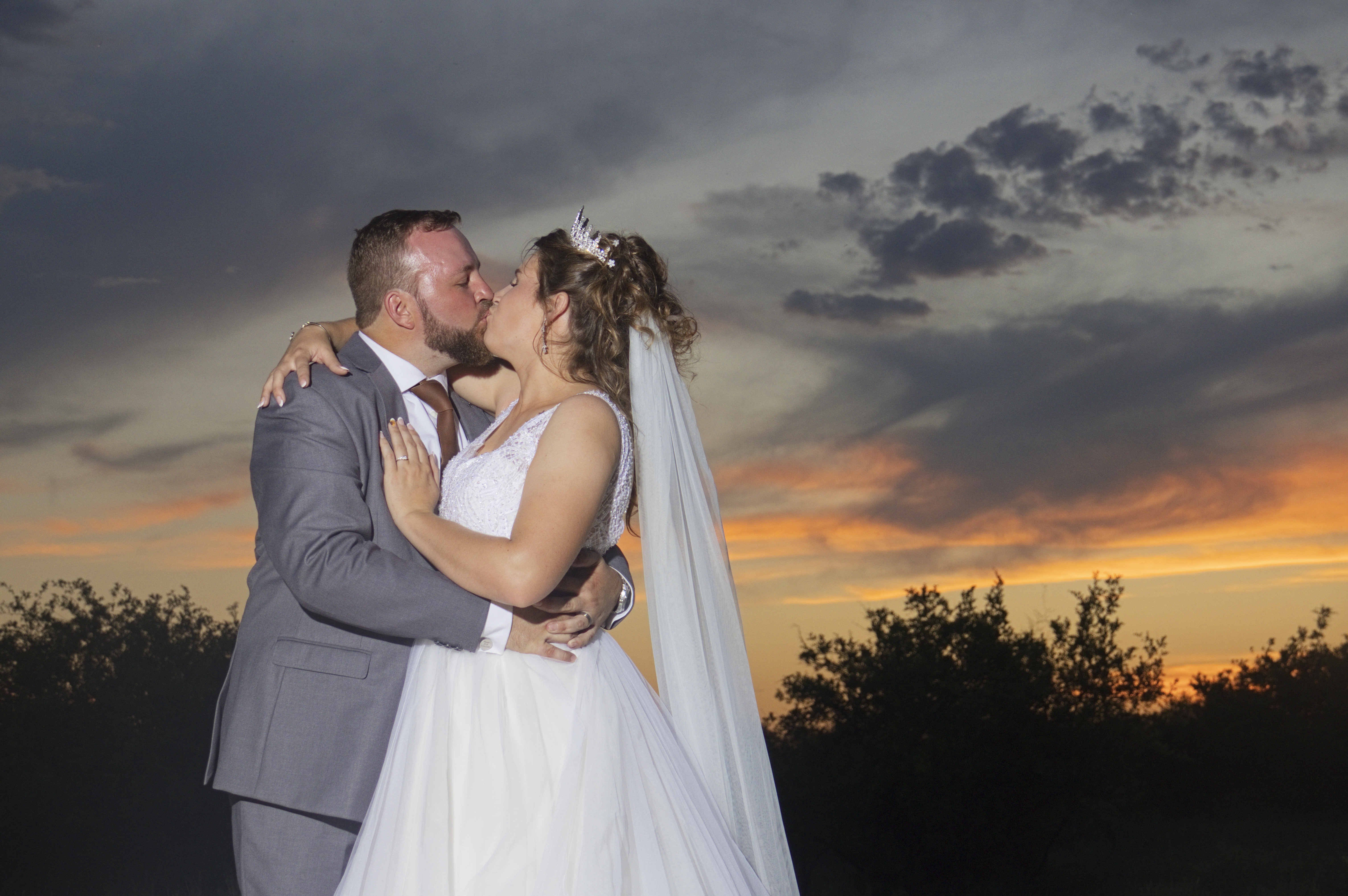 Couple kissing beneath a dramatic dusk sky