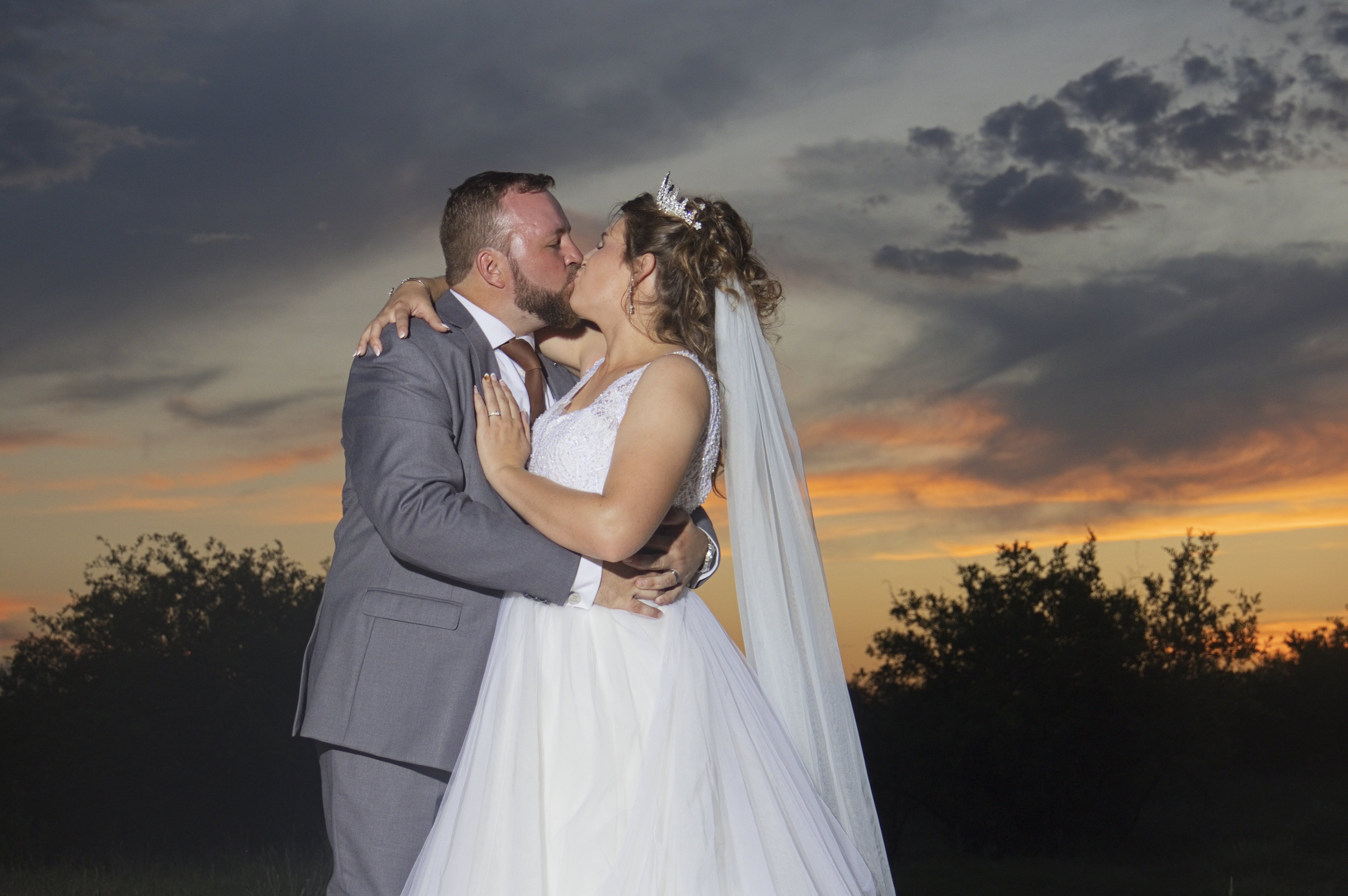 Couple sharing a kiss at dusk with the veil trailing