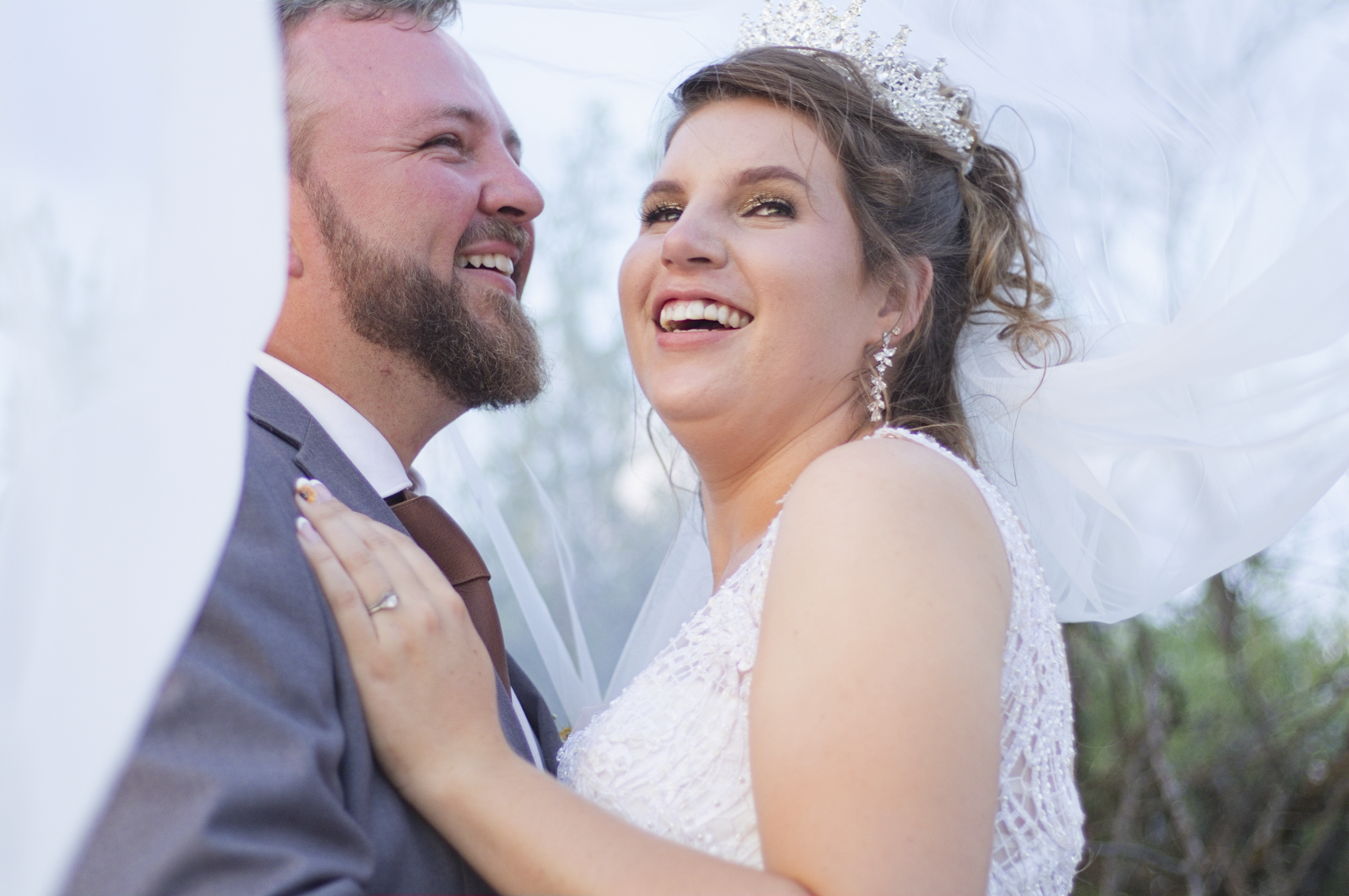 Bride and groom laughing together under the veil