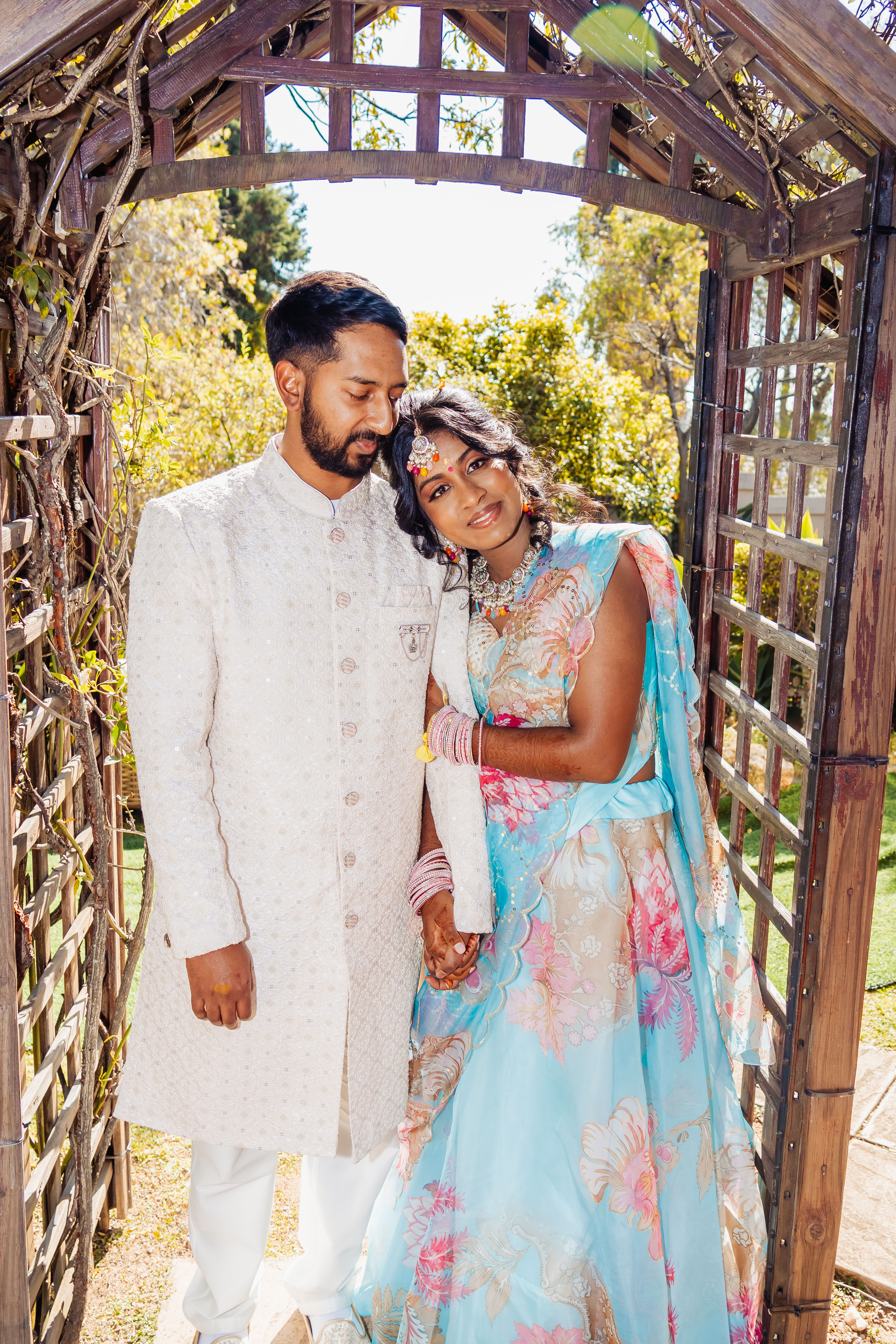 Couple in traditional attire beneath a wooden garden arch