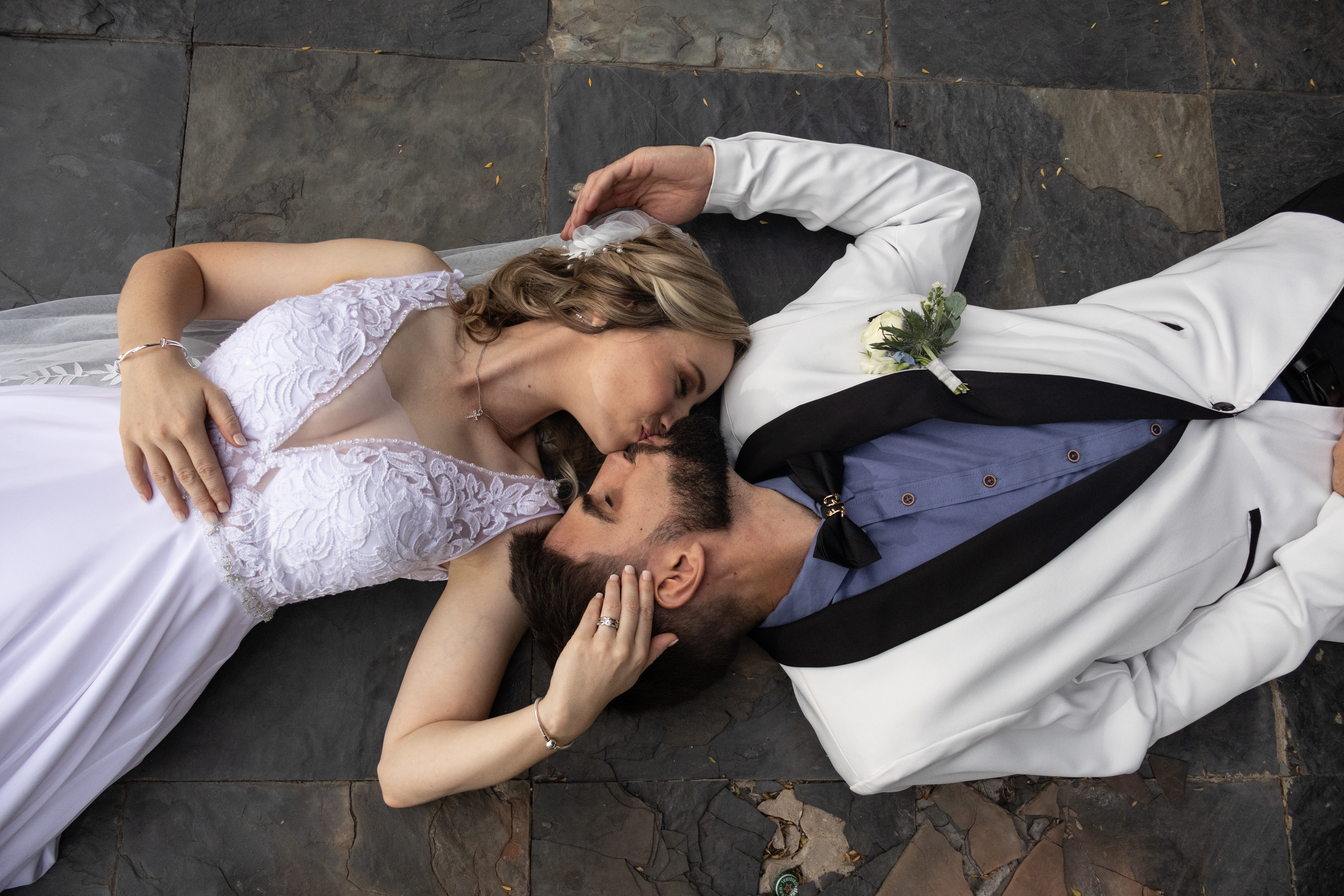 Overhead view of the couple lying on stone tiles sharing a kiss
