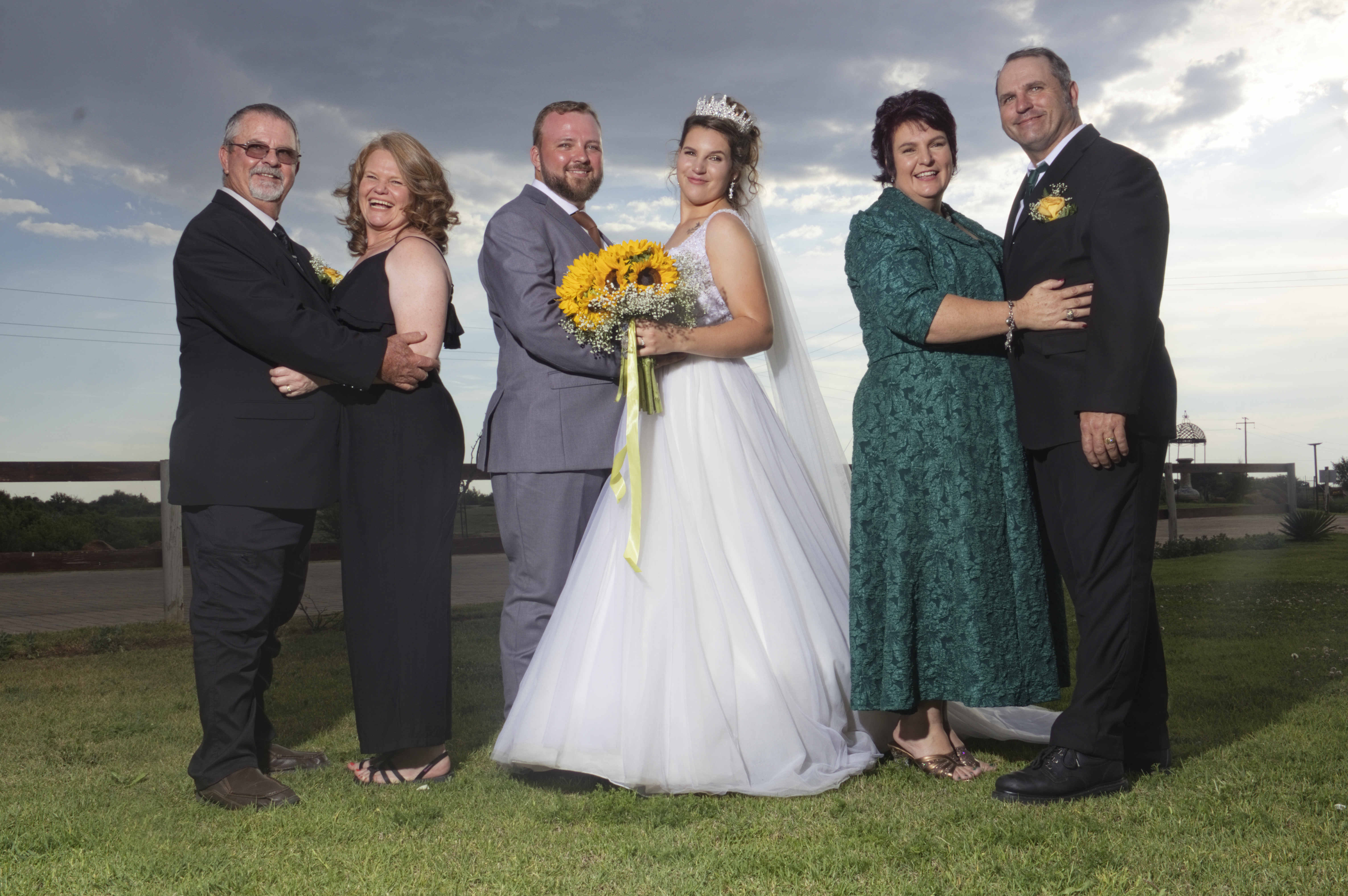 Bride, groom and parents embracing as couples
