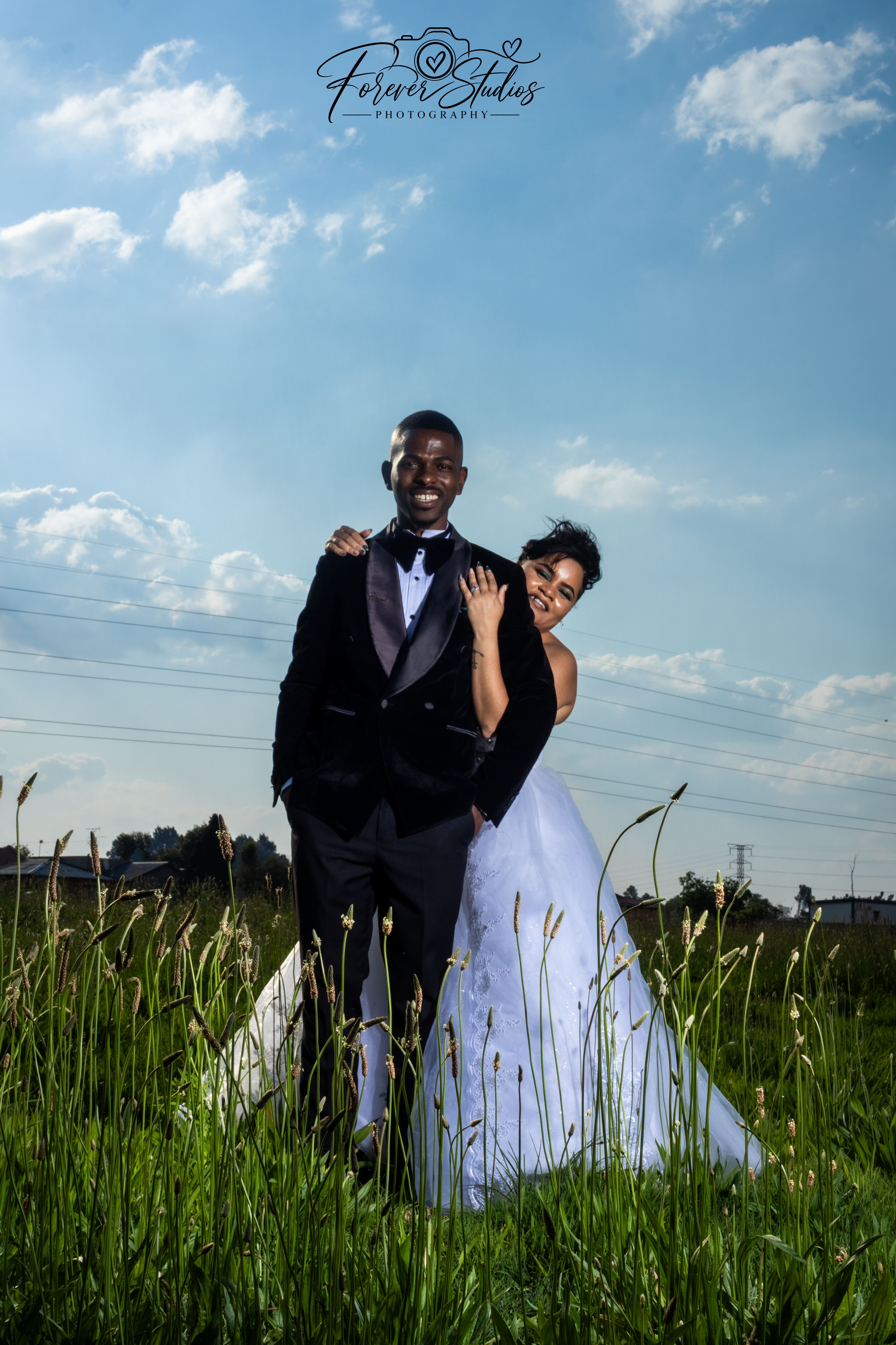 Bride peeking over the groom's shoulder in a grassy field