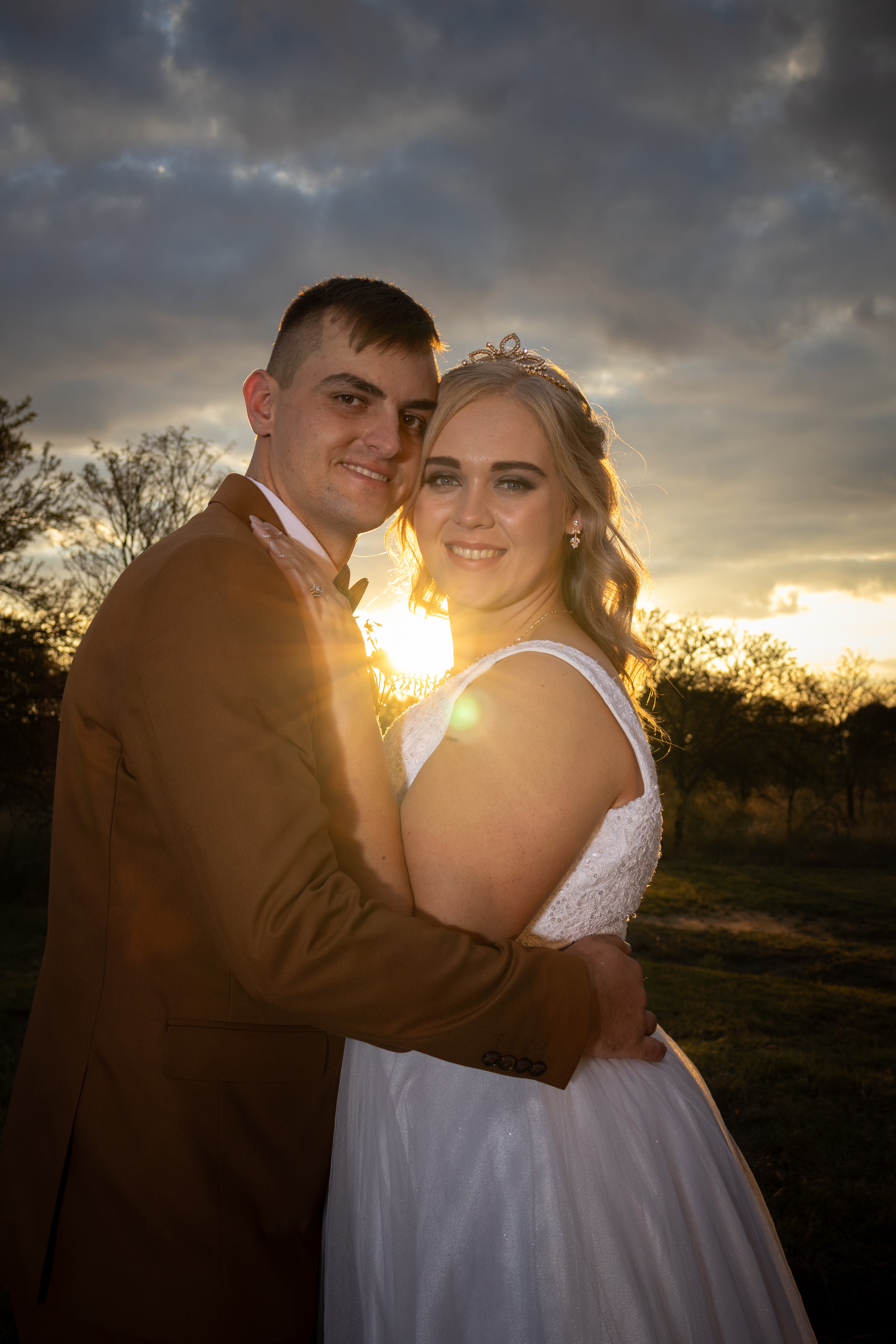 Couple embracing with the setting sun flaring behind them