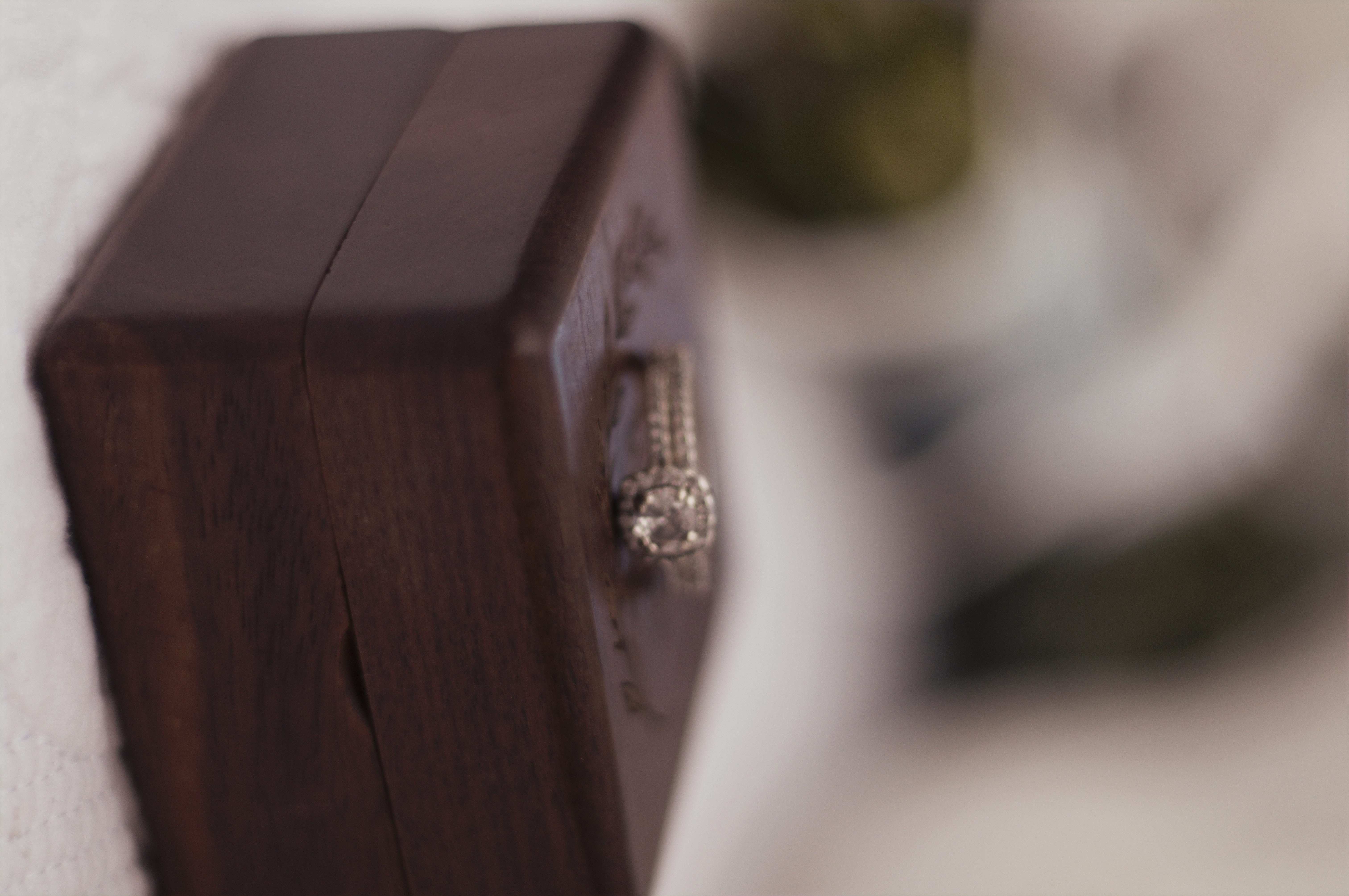 Diamond engagement ring resting on a wooden ring box