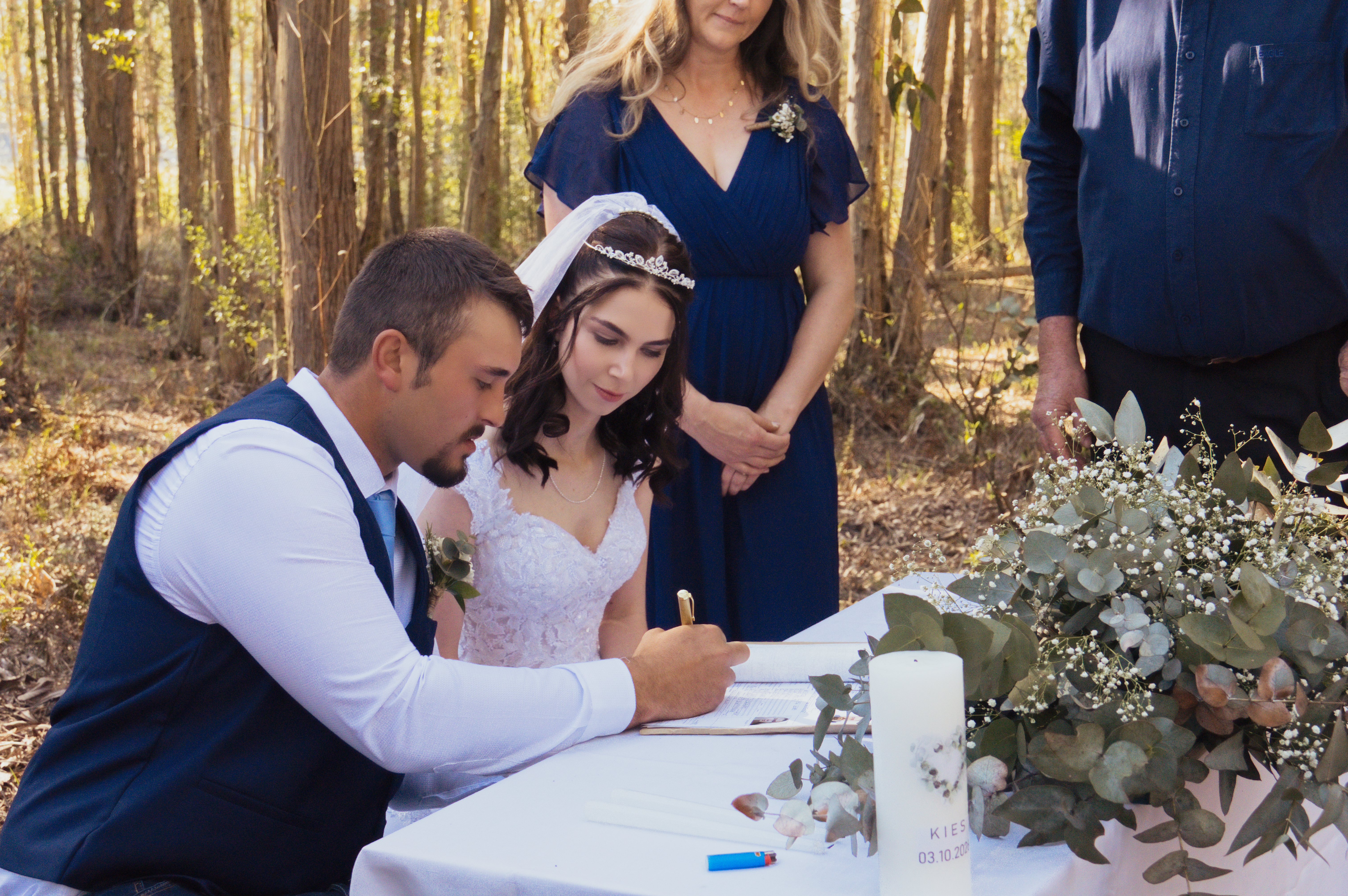 Couple signing the marriage register at an outdoor forest ceremony