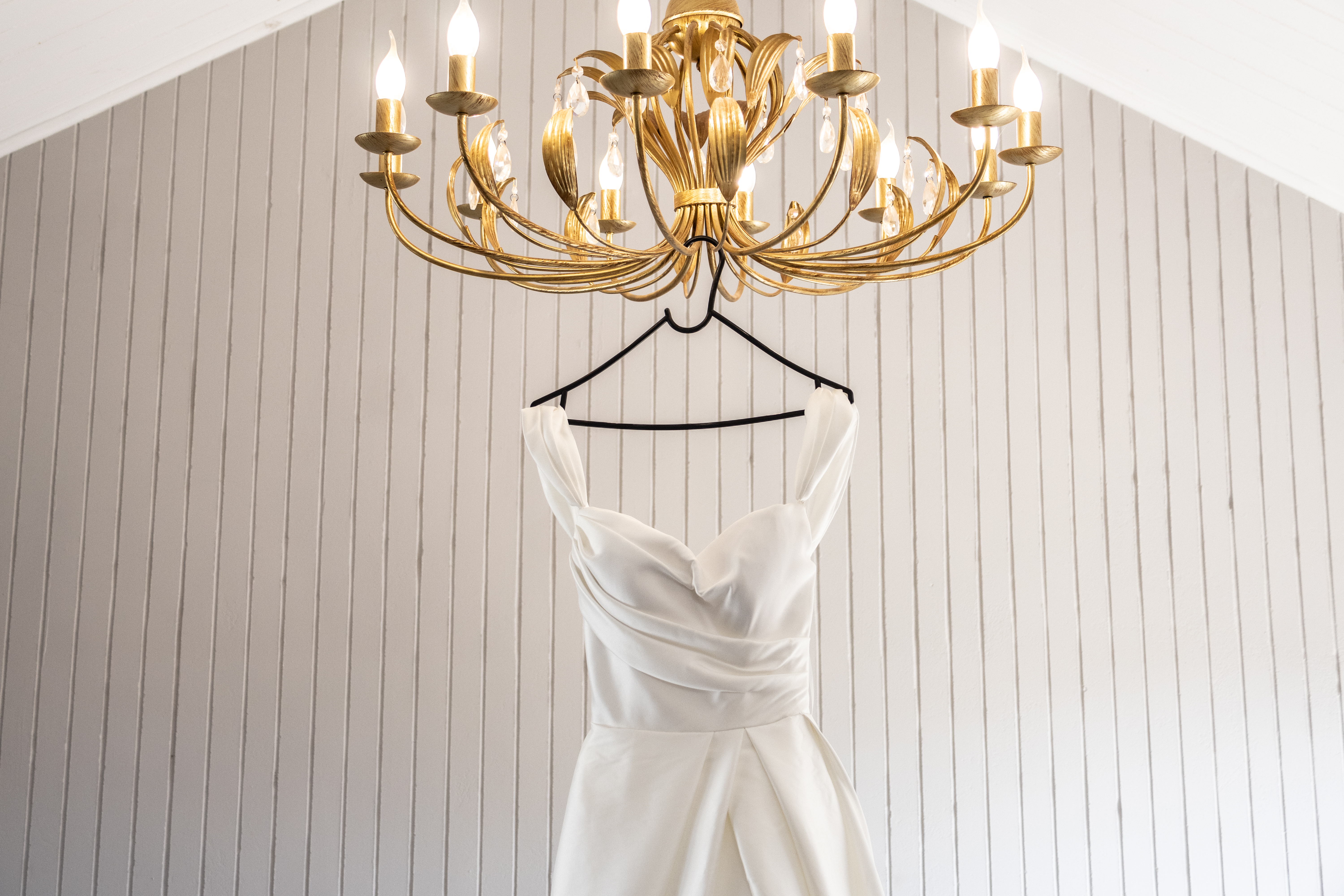 Wedding gown hanging from an ornate gold chandelier