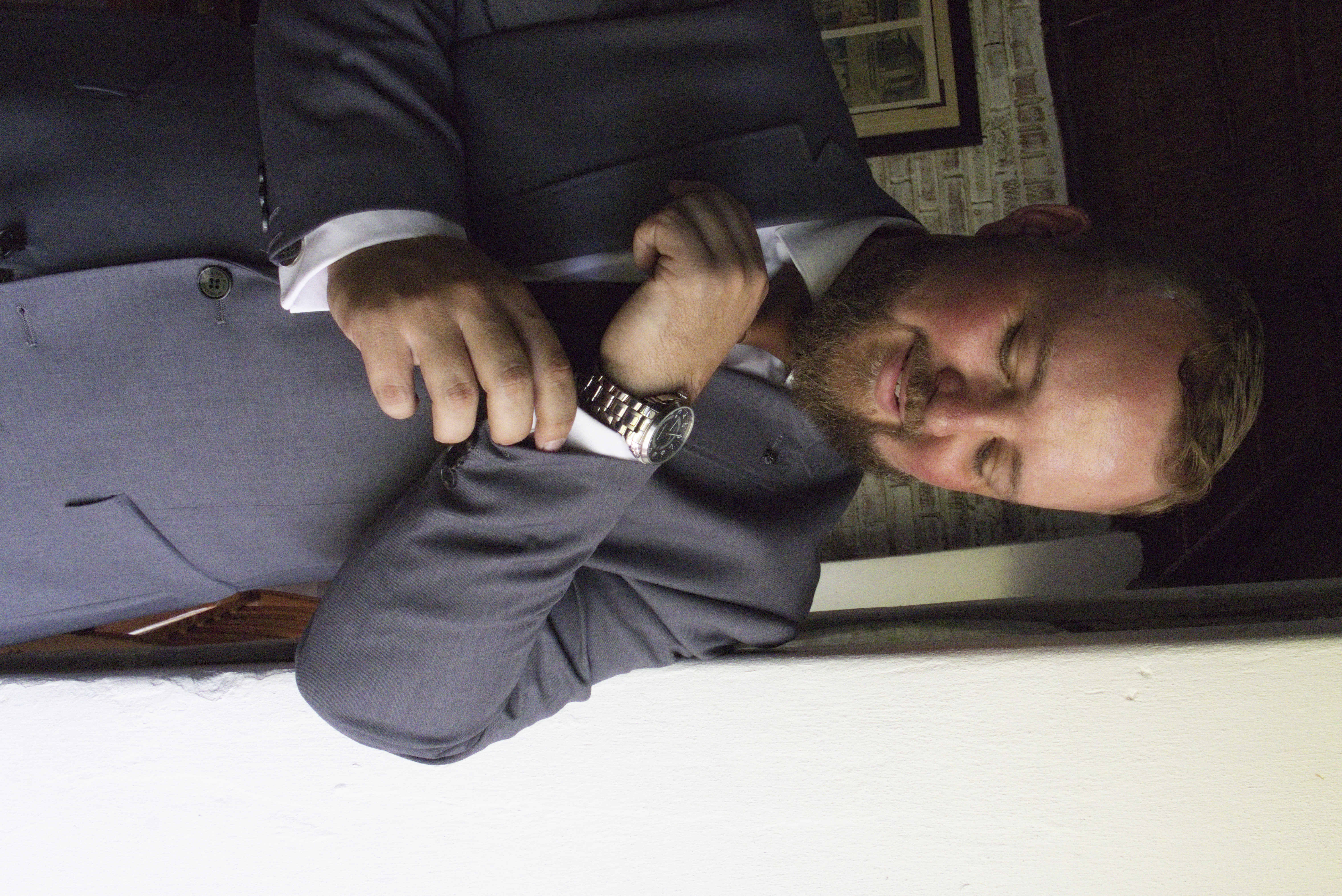 Groom smiling as he adjusts his cufflinks