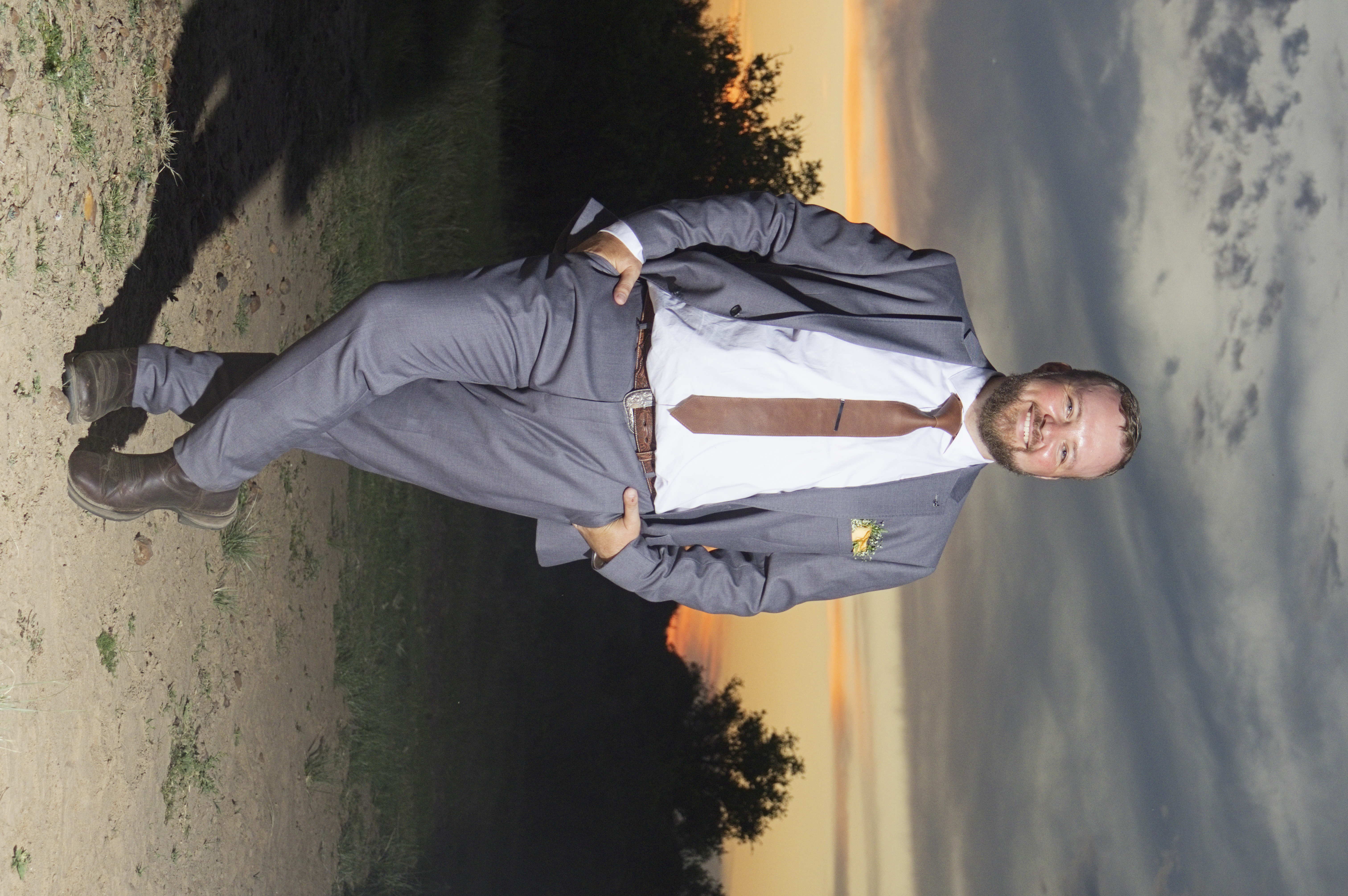 Smiling groom standing under a moody dusk sky