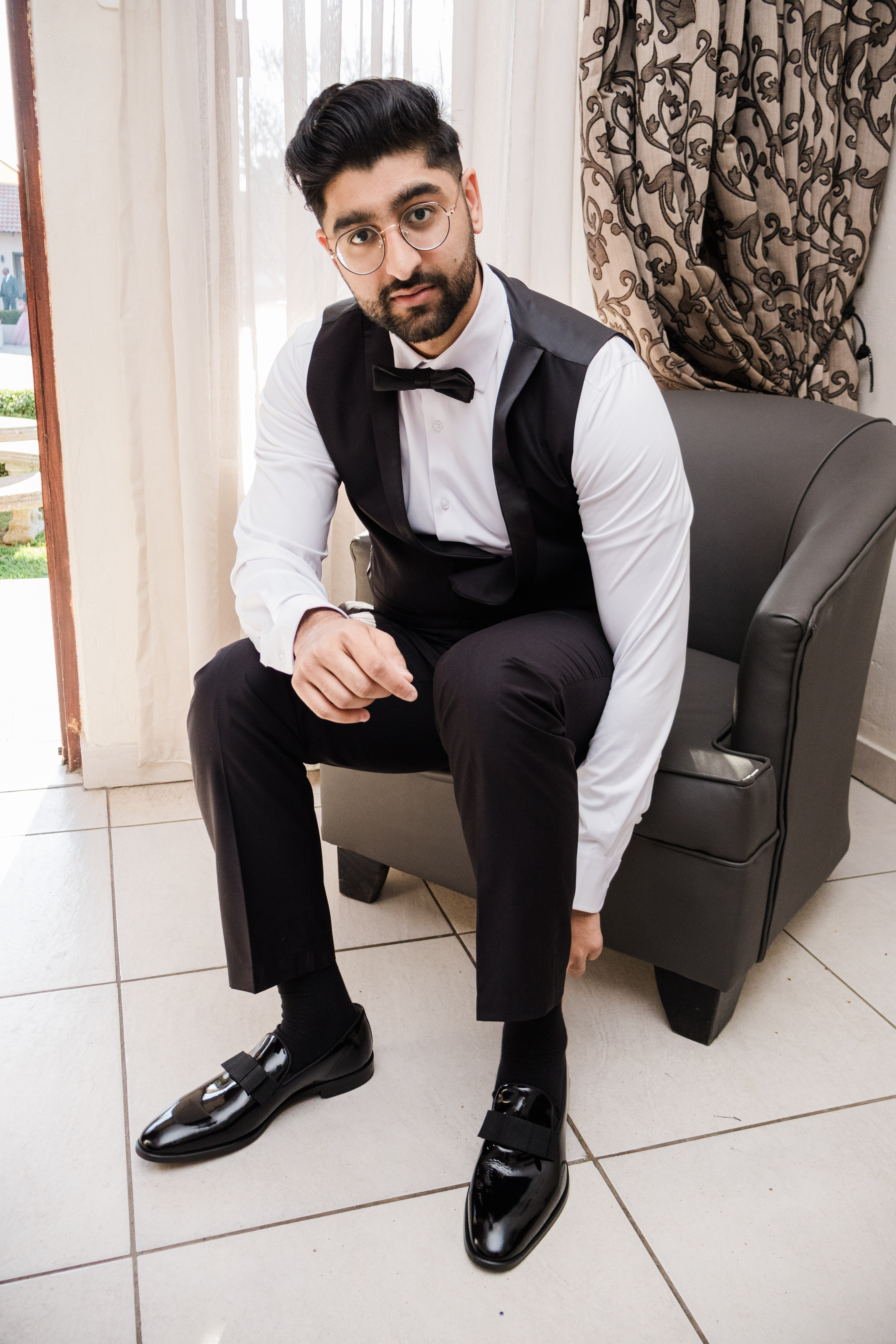 Groom in a bow tie and waistcoat seated in an armchair