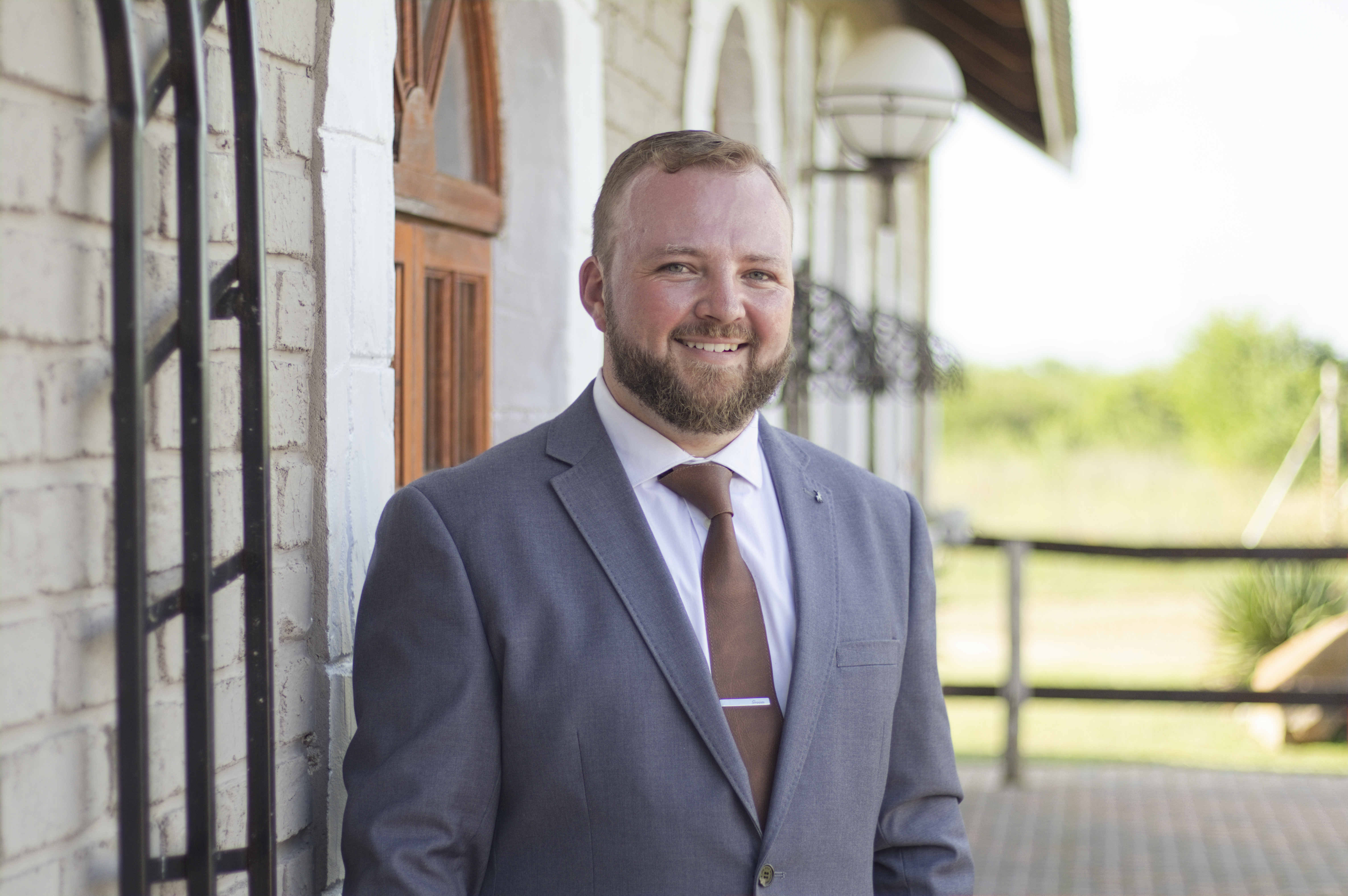 Smiling groom portrait outdoors in a grey suit