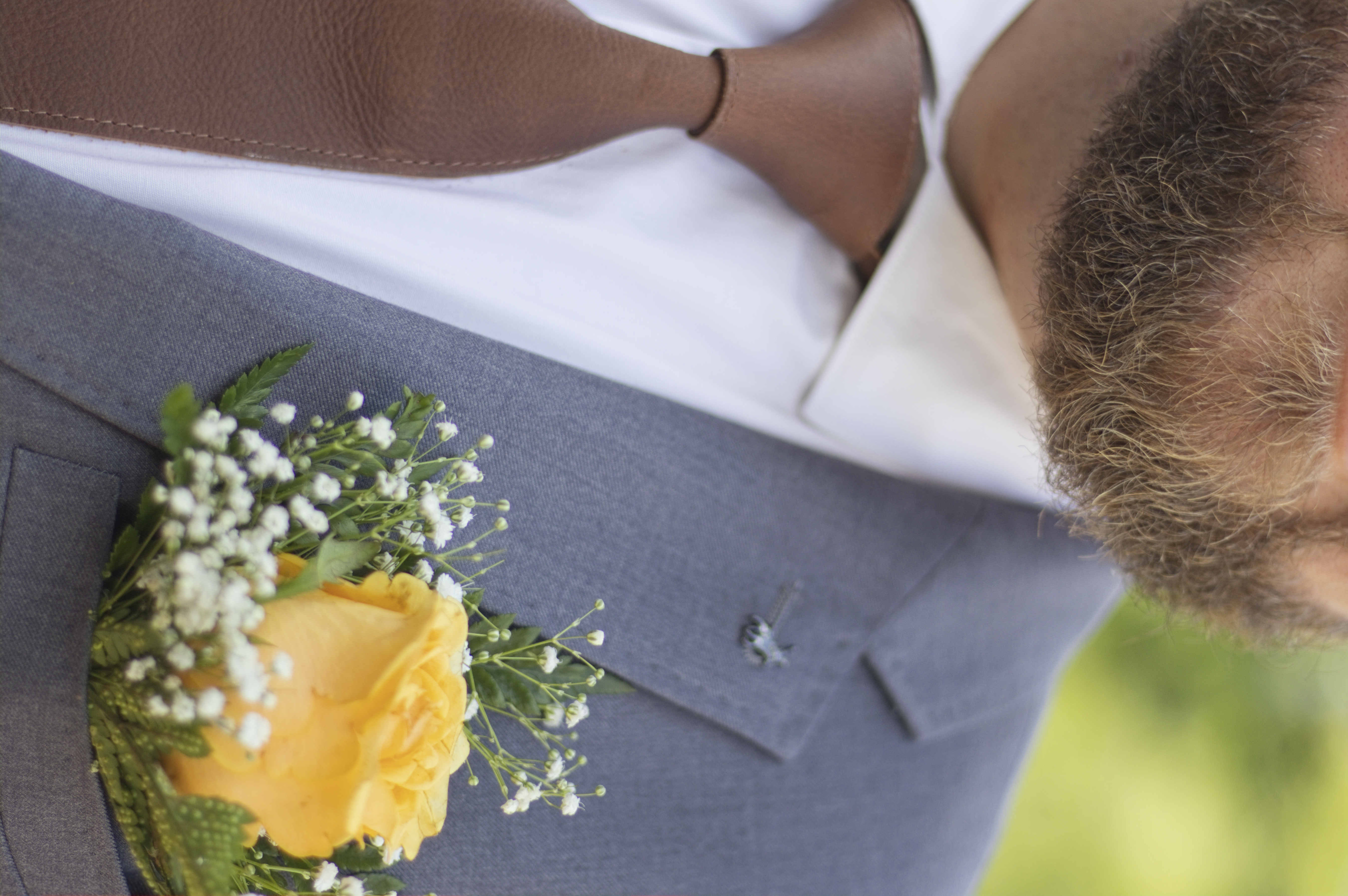 Close-up of a yellow rose boutonniere and leather tie