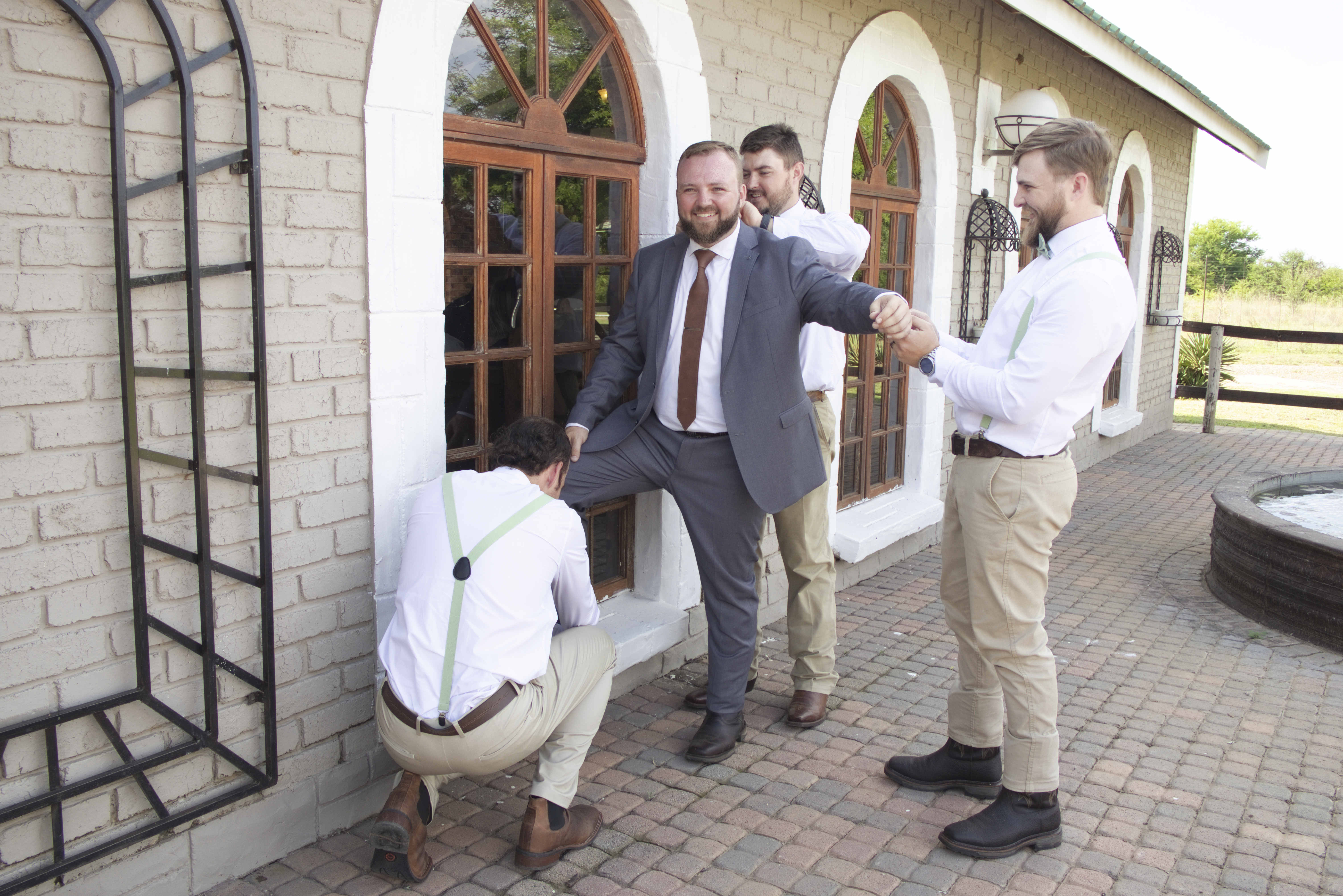 Groomsmen helping the groom get ready outdoors