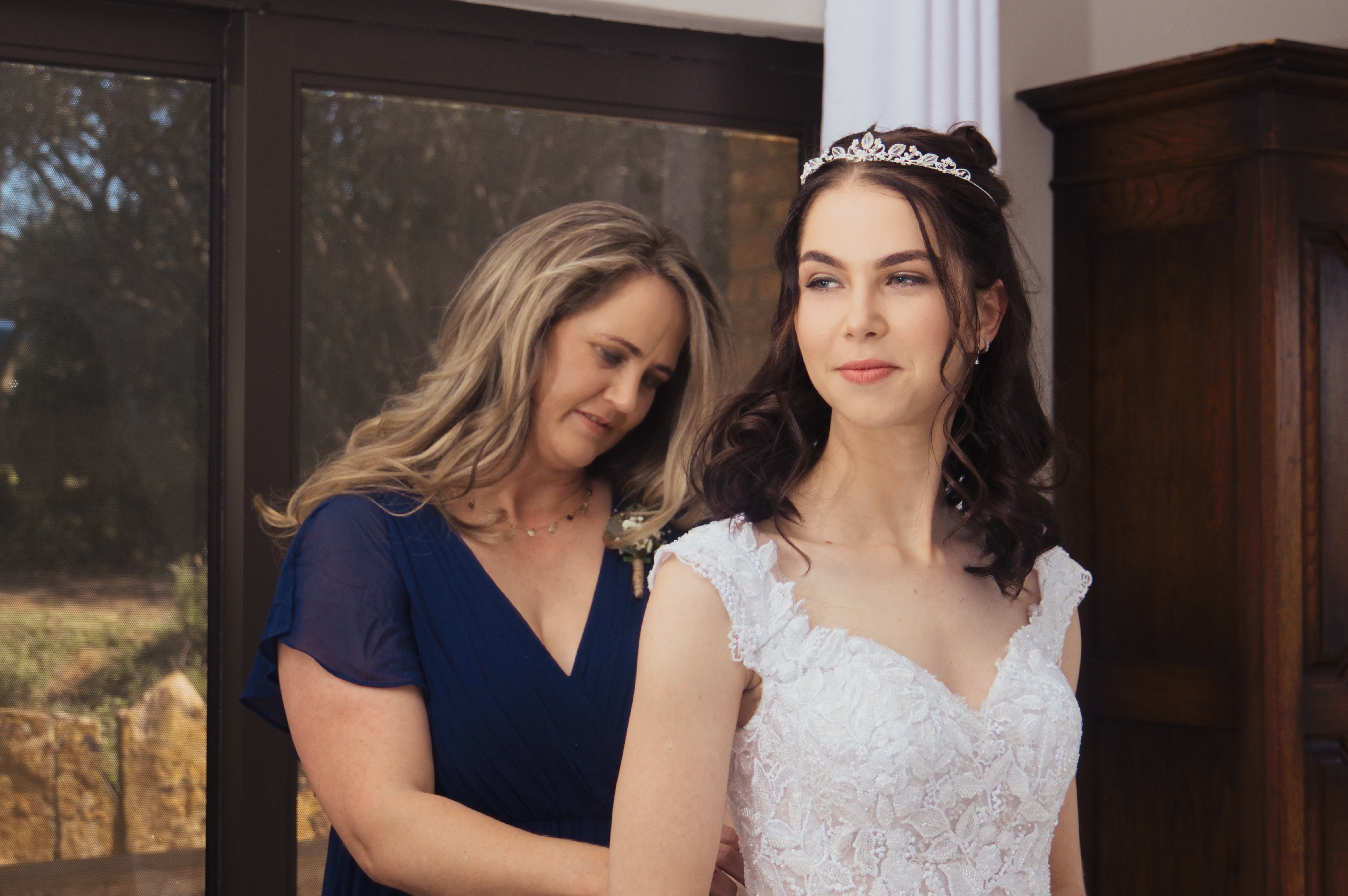 Mother helping the bride into her lace gown